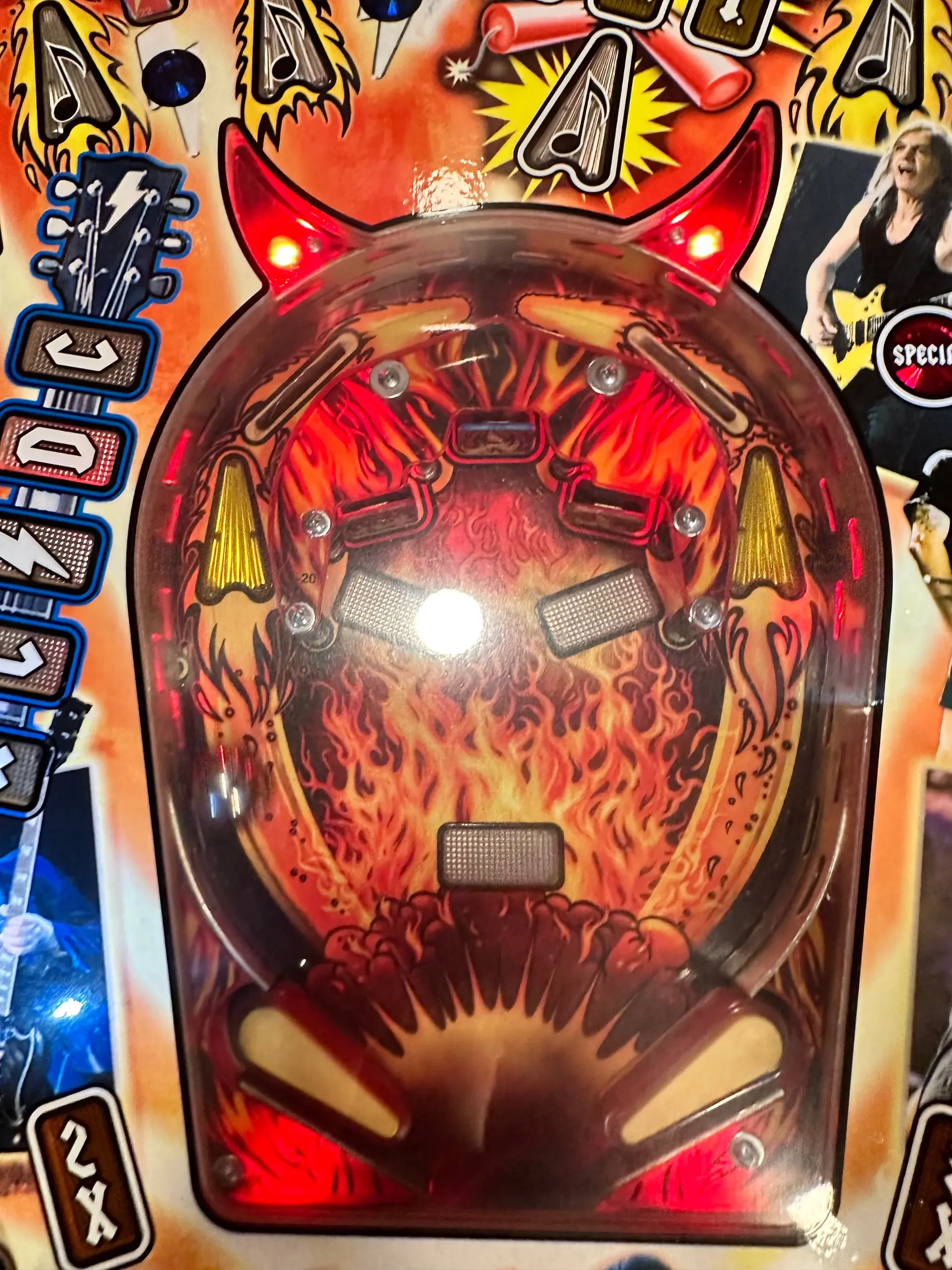 Fiery pinball machine backglass with devil-like design and glowing red elements
