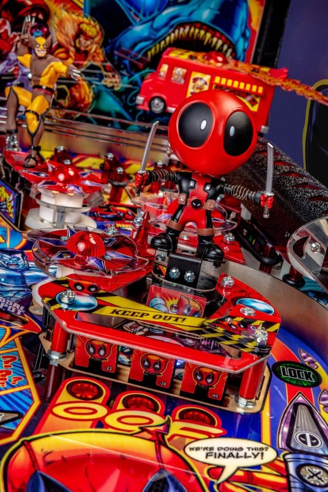 Colorful Deadpool-themed pinball machine with red cartoon character and comics
