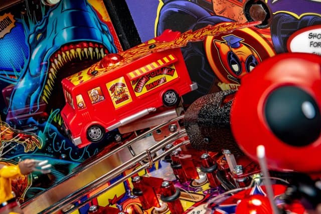 Colorful pinball machine with red bus, shark, and cartoon characters