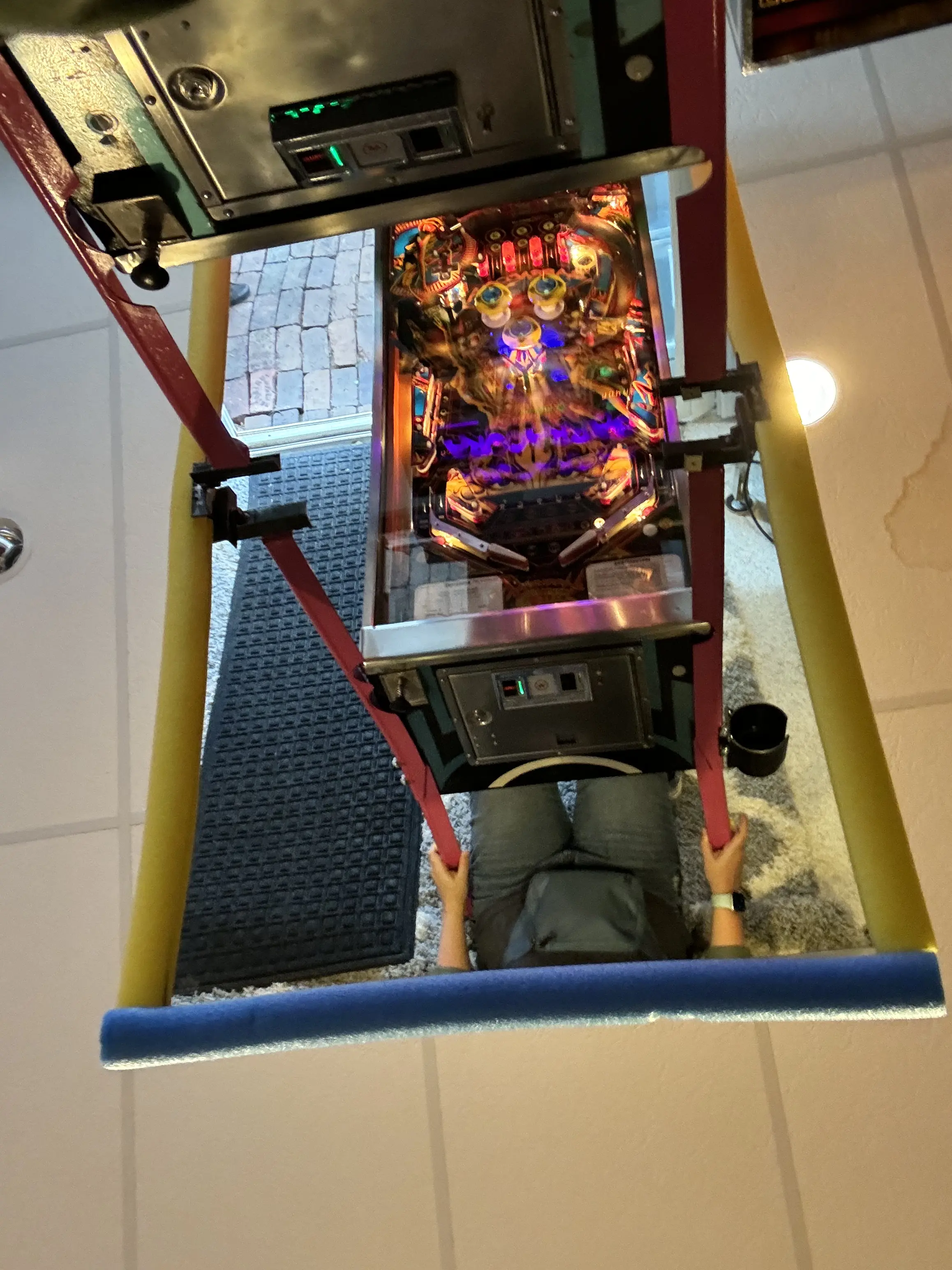 Colorful pinball machine viewed from above, mounted on red supports