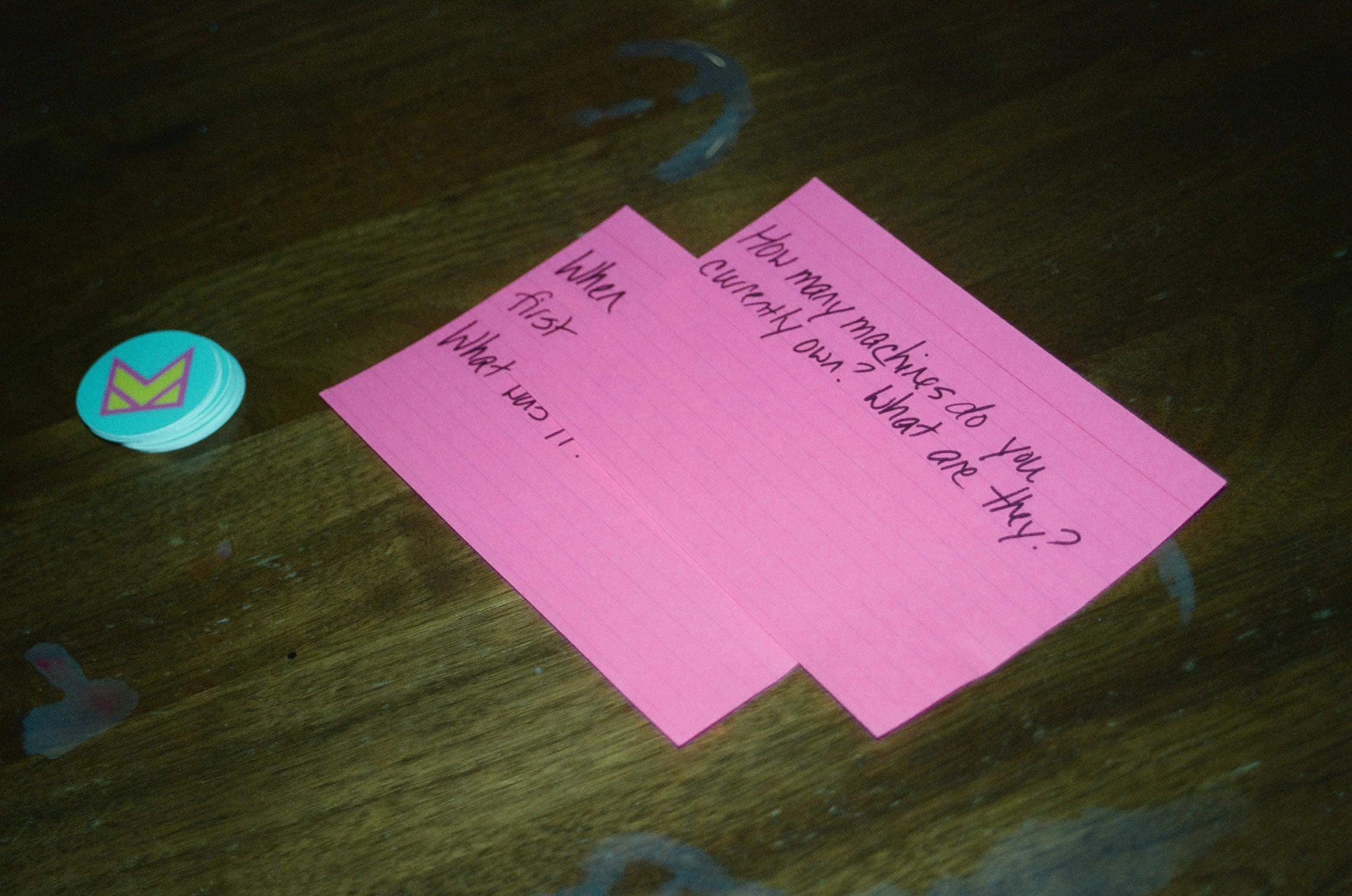 Pink sticky notes with handwritten text on wooden surface with blue pin