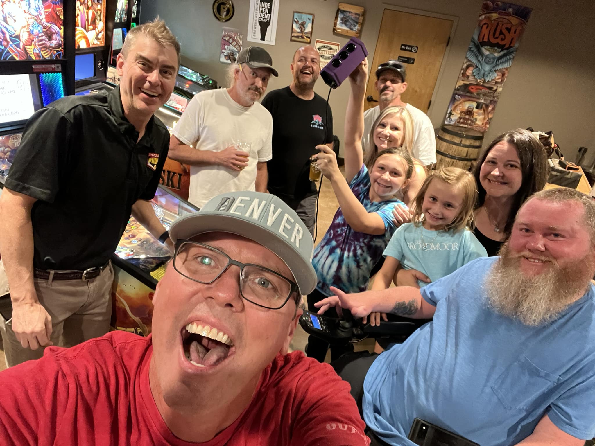 Excited group selfie in game room with adults and children smiling