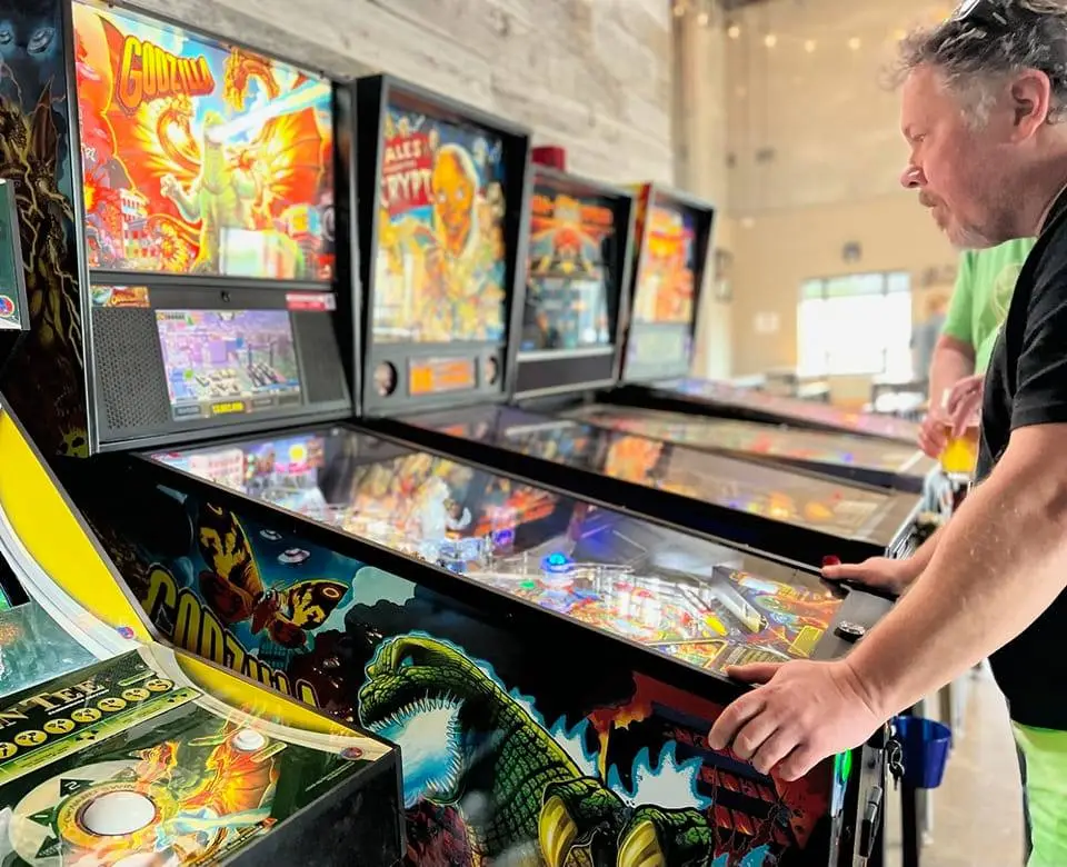 Godzilla pinball machine with colorful artwork and player at arcade