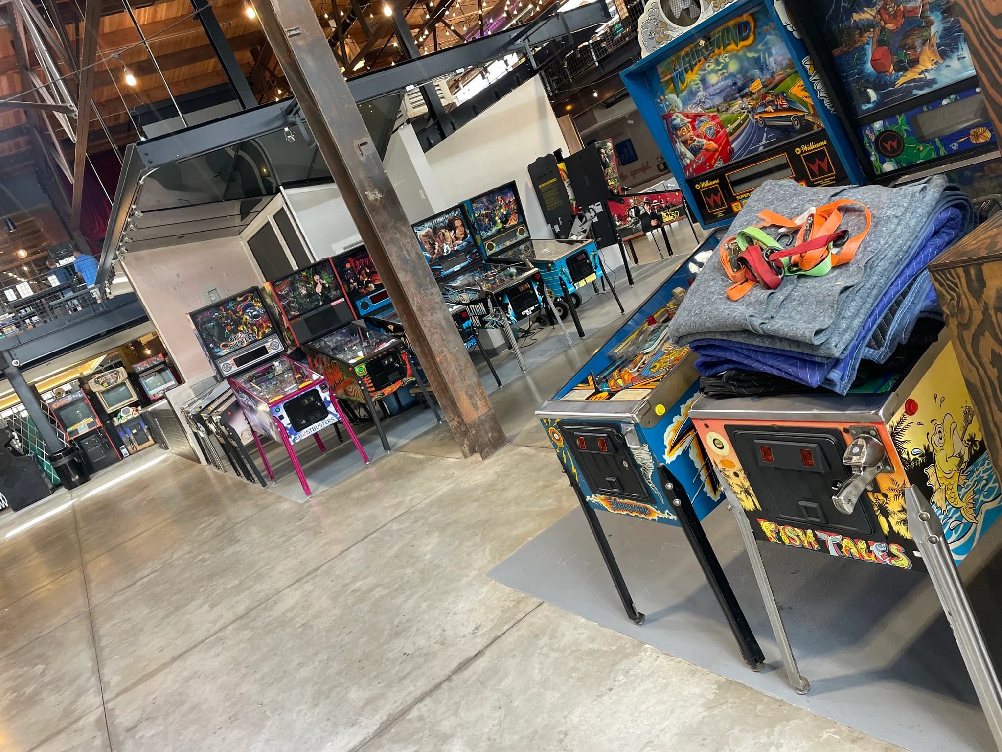 Colorful pinball machines displayed in a spacious industrial-style arcade room