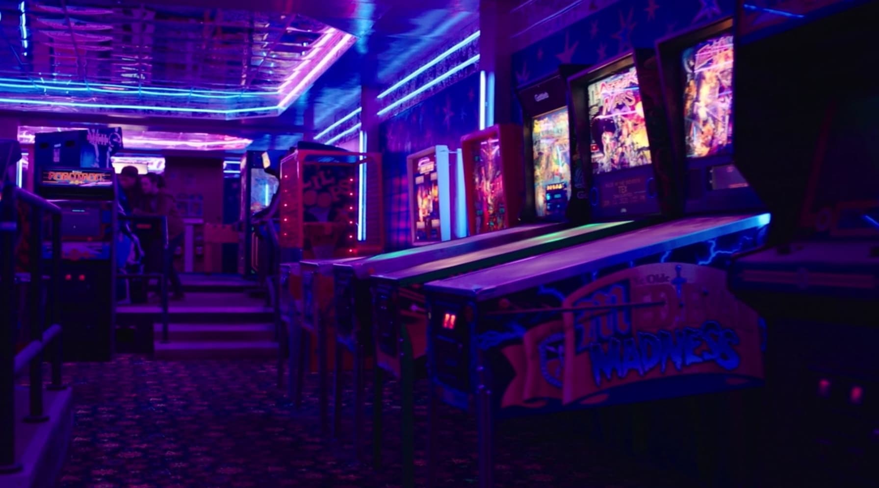 Neon-lit arcade with colorful game machines and vibrant blue-purple lighting