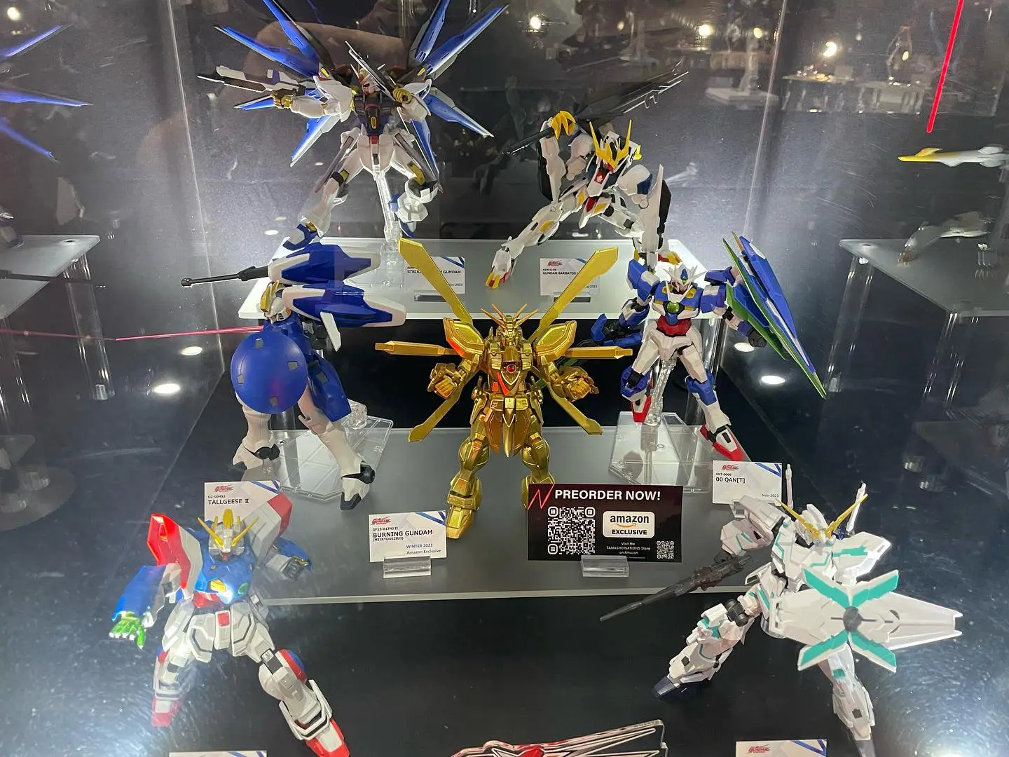 Gundam model figures displayed in glass case with preorder information