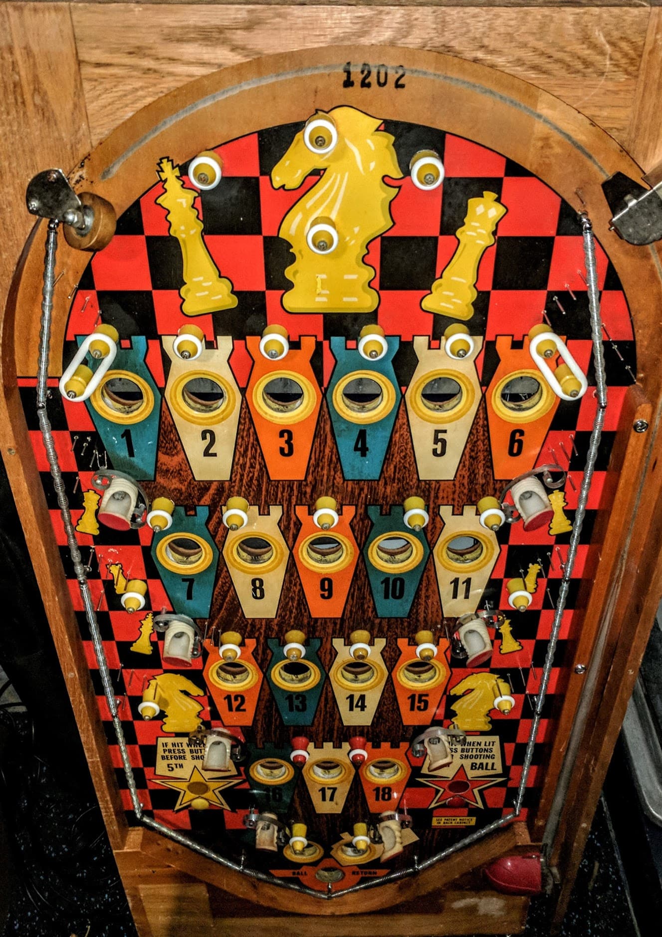 Vintage pinball machine playfield with chess-themed design and numbered targets