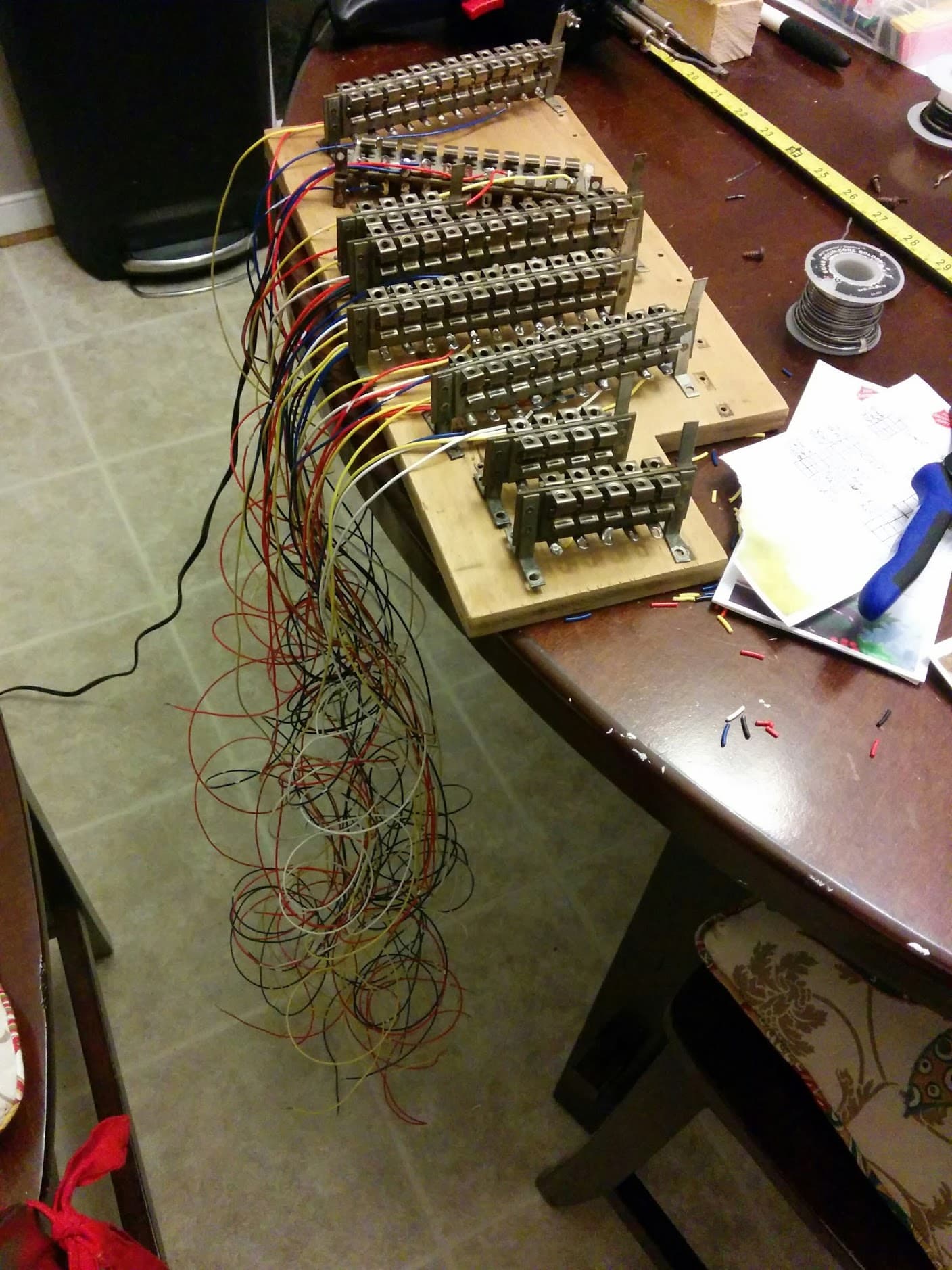Tangled colorful wires connected to electrical terminal blocks on wooden board