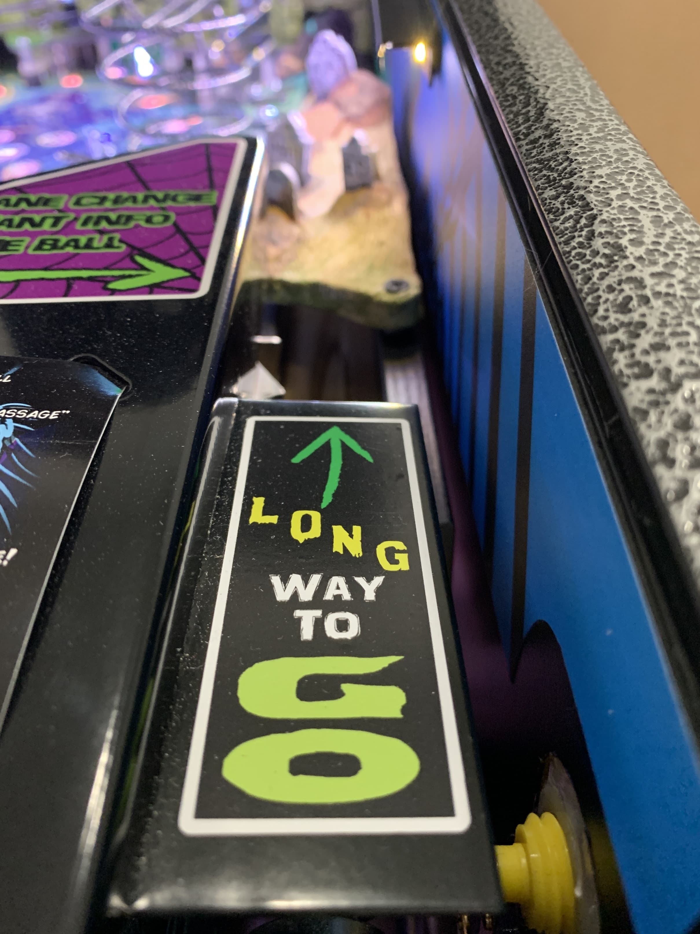 Pinball machine closeup showing "Long Way to Go" sign with colorful lights