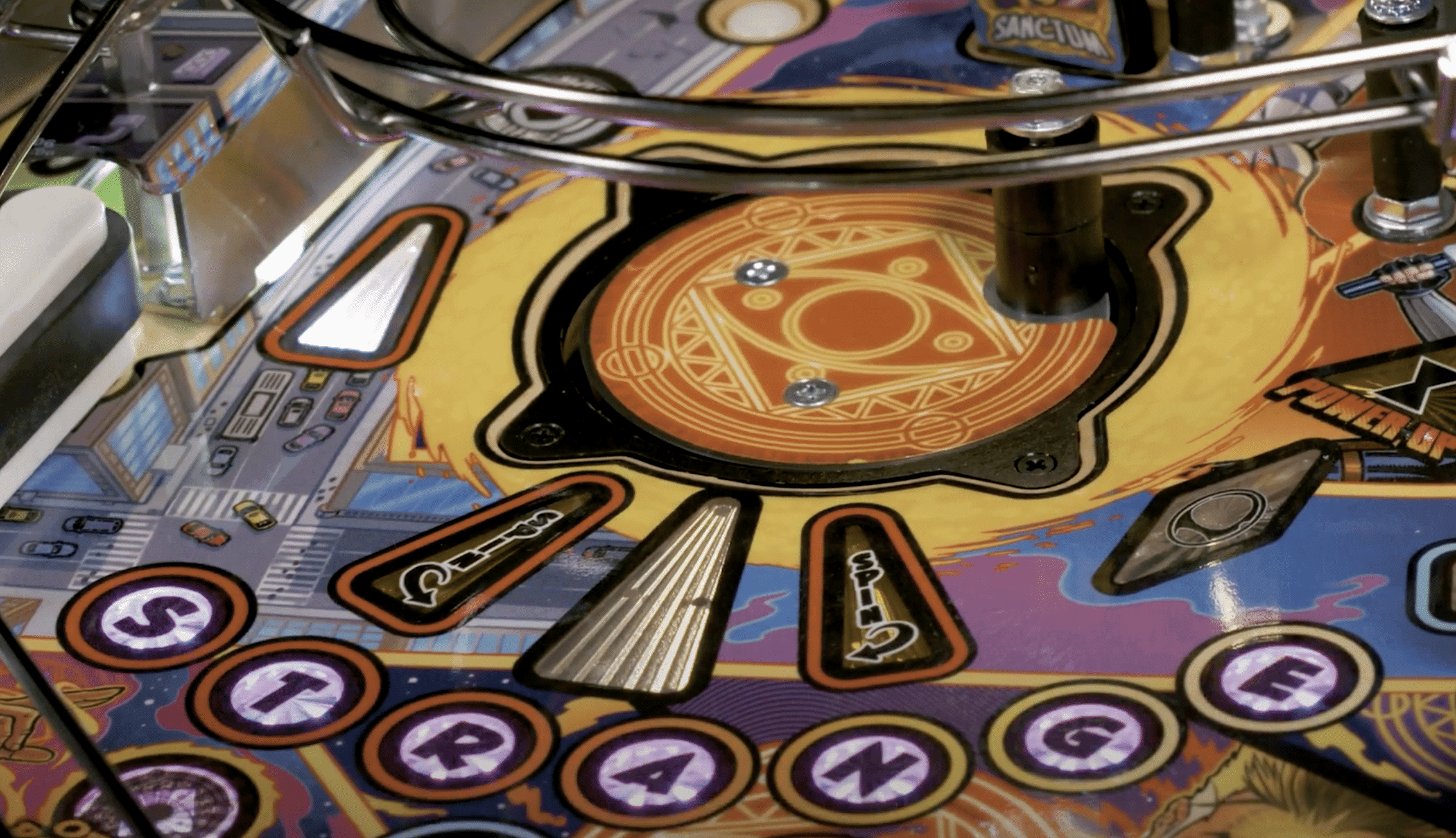 Colorful pinball machine playfield with intricate design and letter buttons