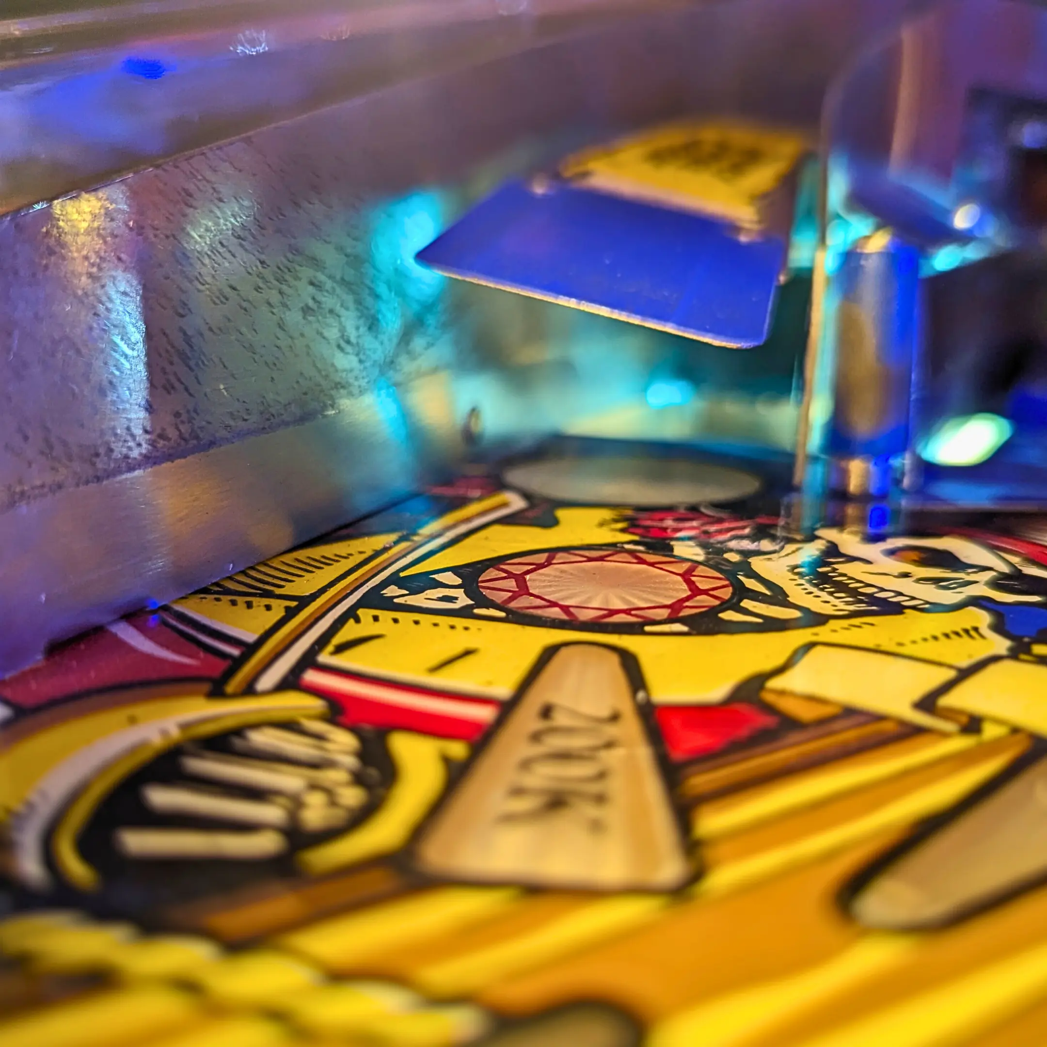 Colorful pinball machine playfield with vibrant blue and yellow lights