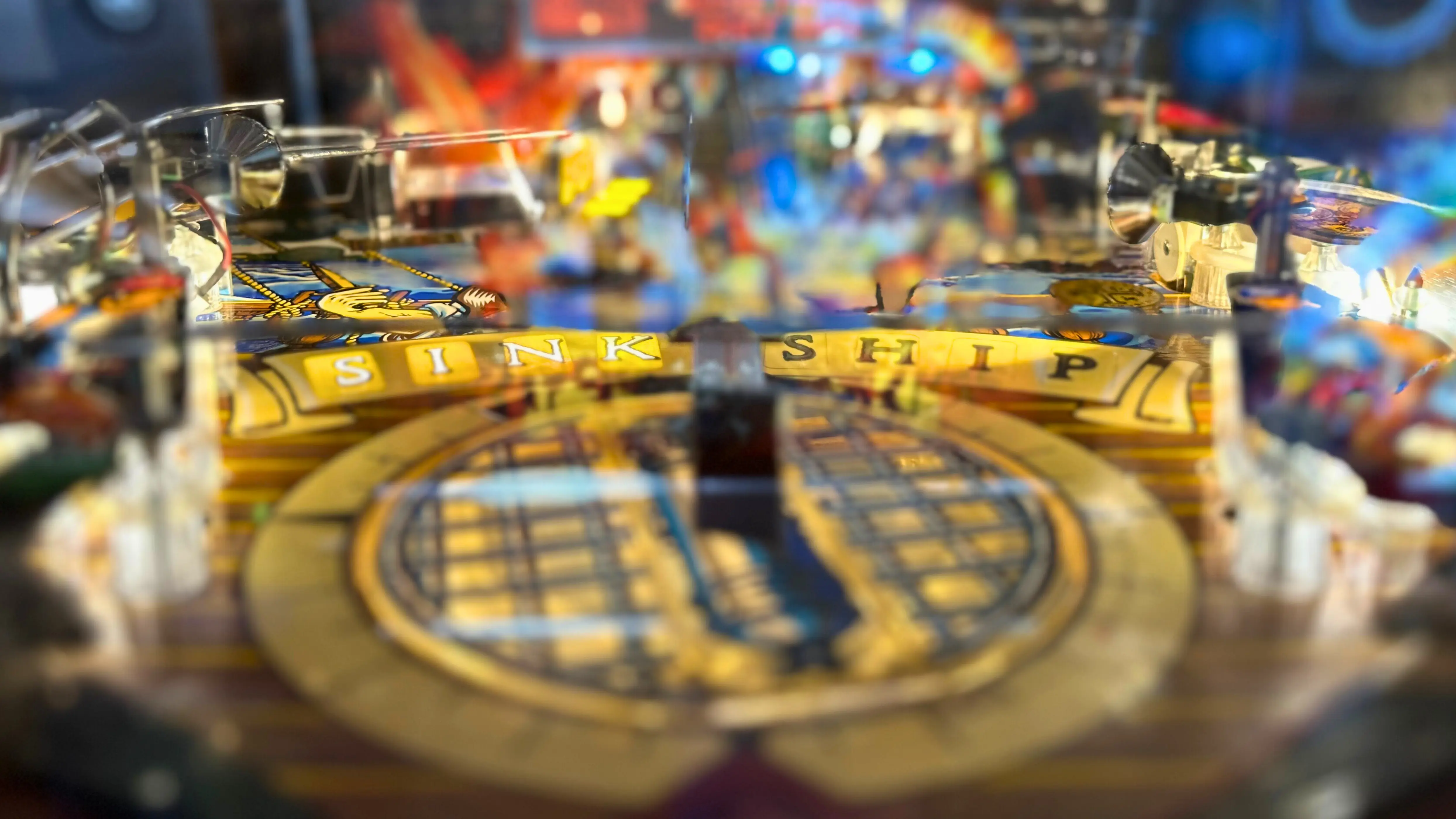 Close-up of a pinball machine with blurry colorful background