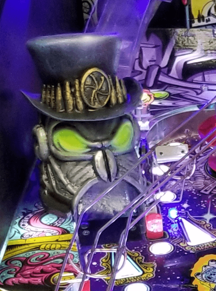 Steampunk owl figurine on colorful pinball machine with glowing eyes