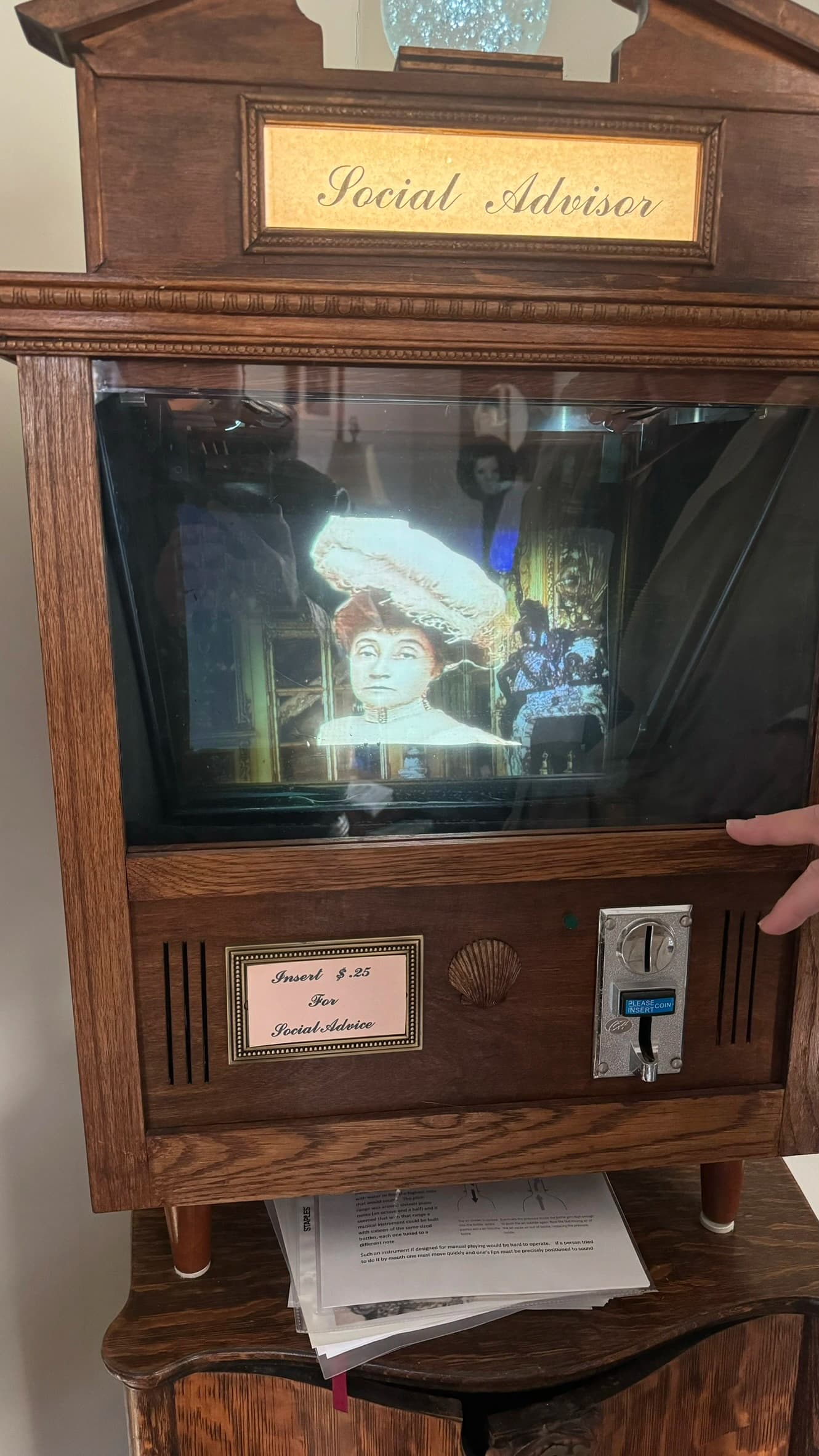 Vintage coin-operated machine displaying holographic woman in elaborate hat
