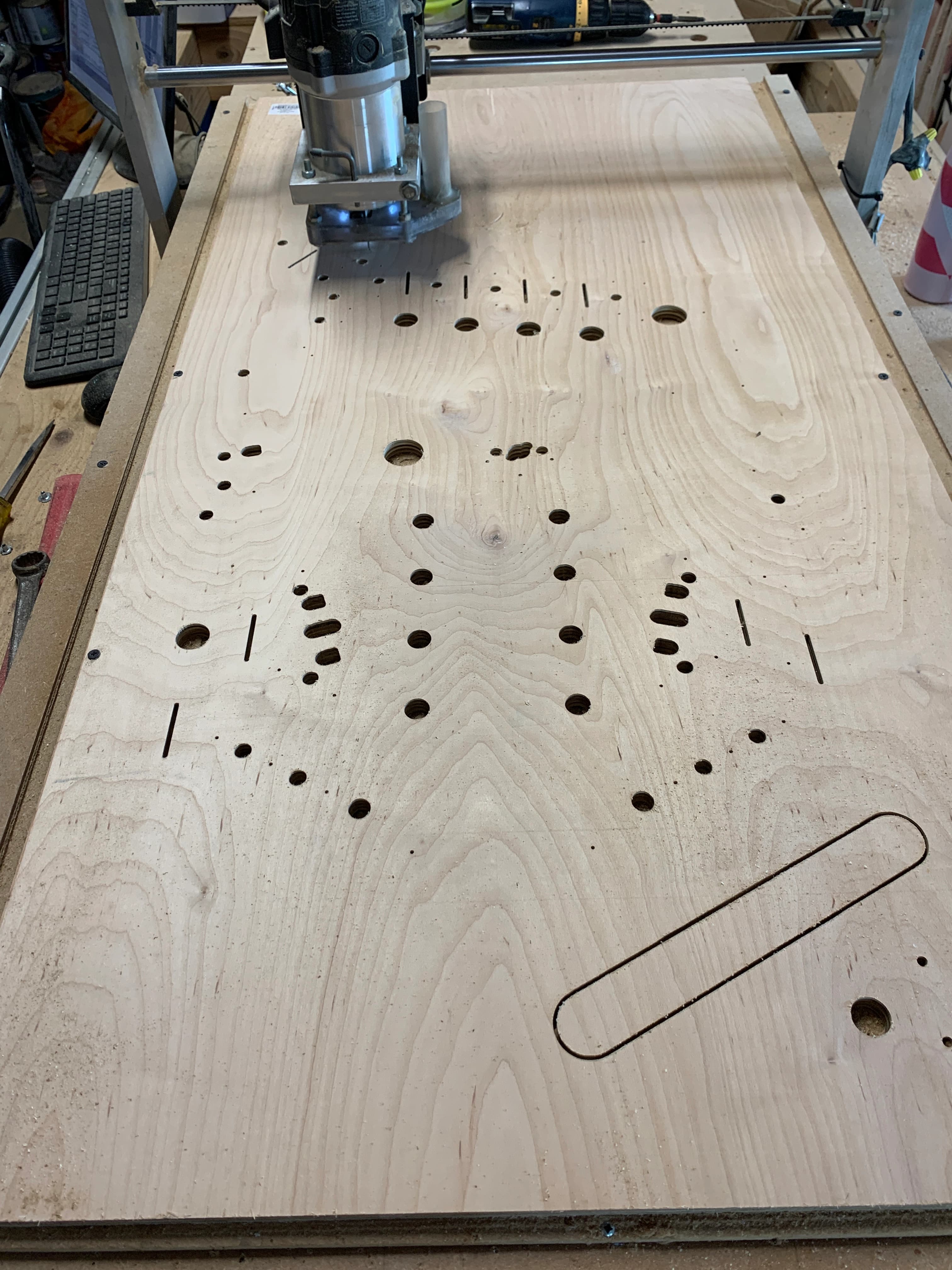 CNC router cutting wooden workboard with multiple precisely drilled holes