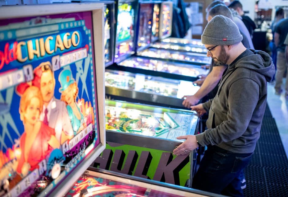Man playing colorful Chicago-themed pinball machine in arcade