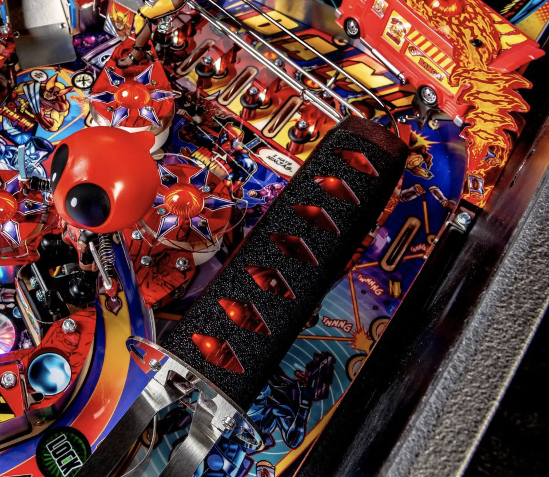 Colorful pinball machine with red robotic creatures and playful graphic design