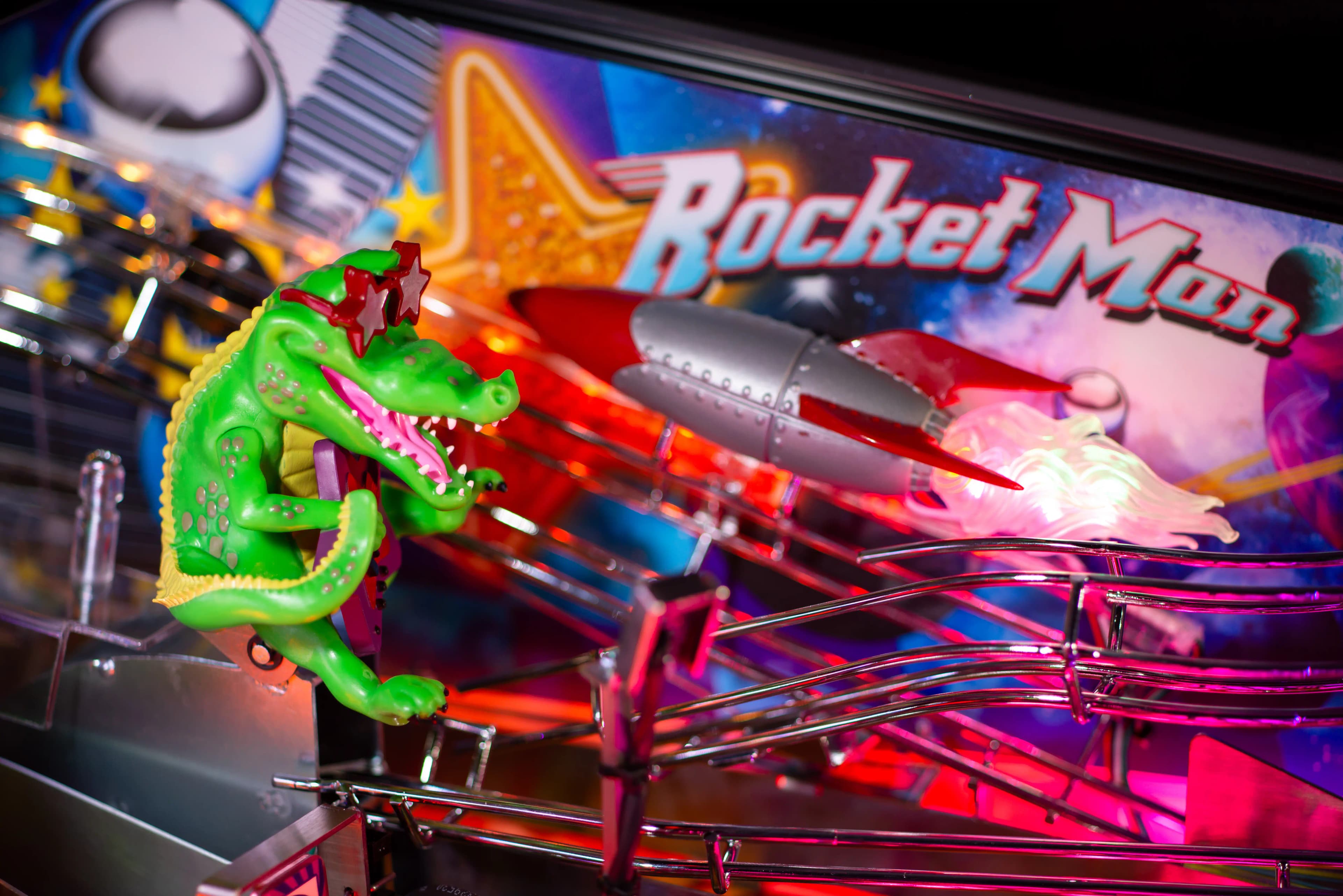 Green dinosaur riding rocket on colorful Rocket Man pinball machine