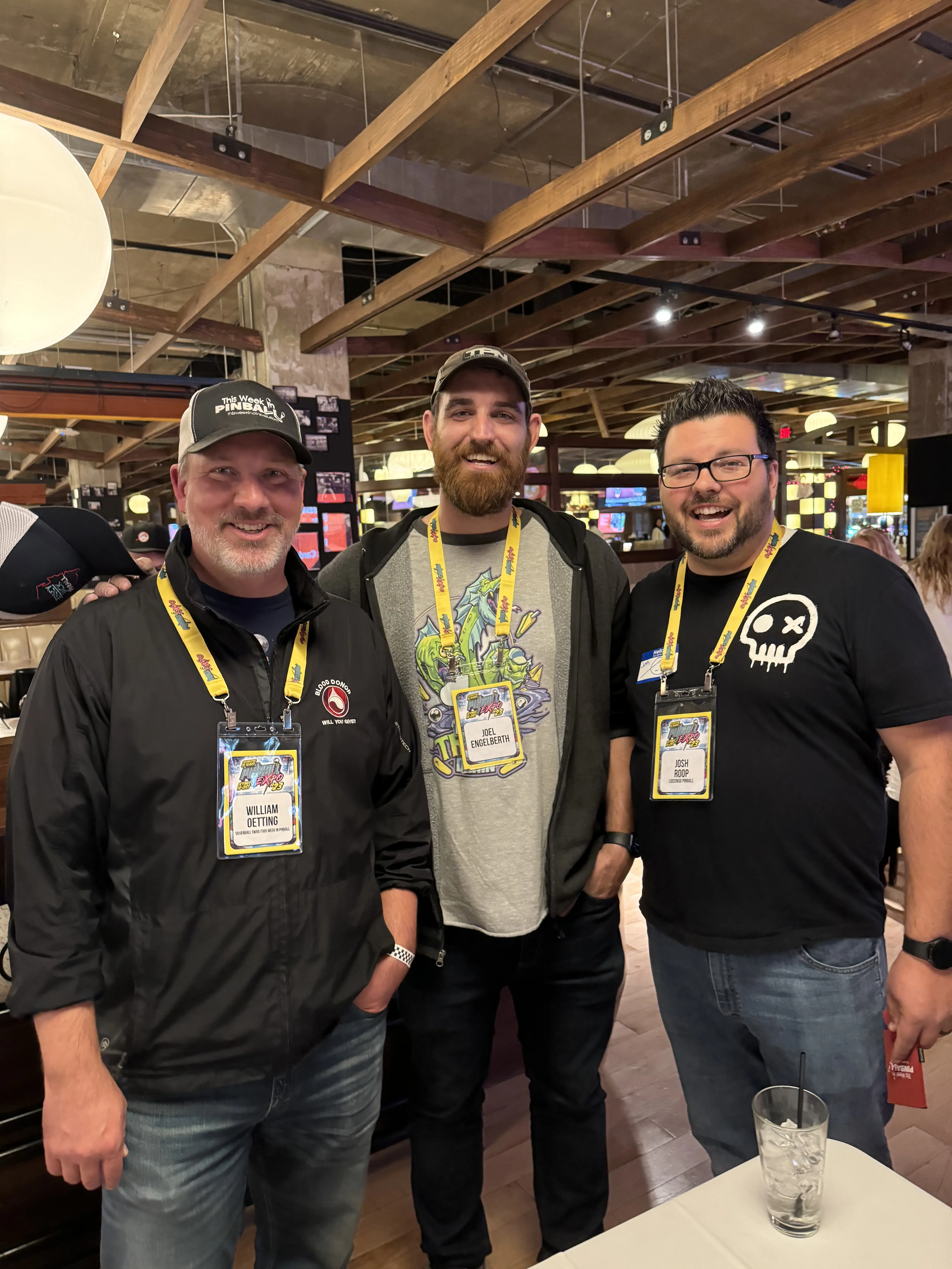 Three men at conference wearing lanyards and smiling together
