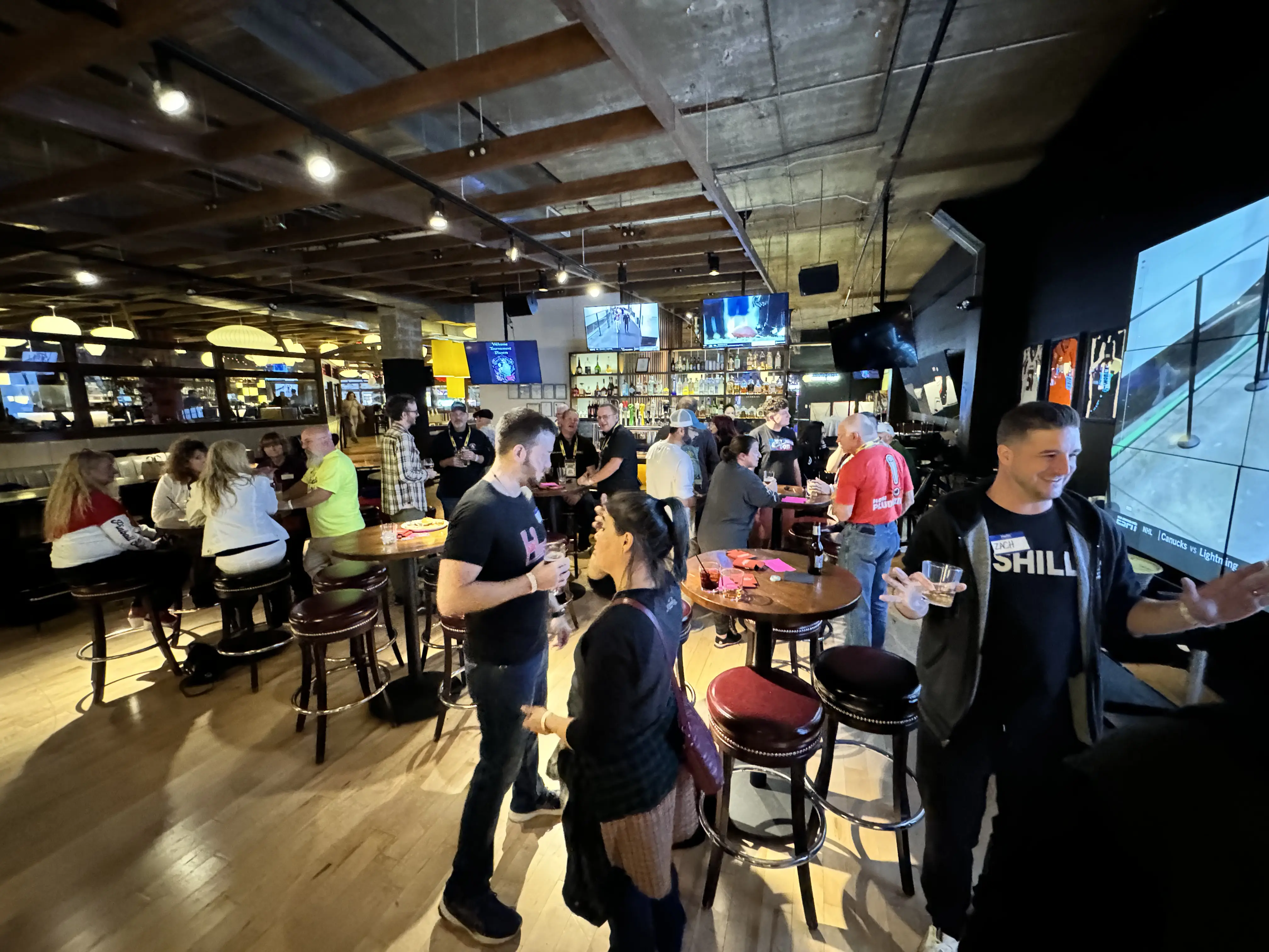 Busy sports bar with people drinking and watching screens