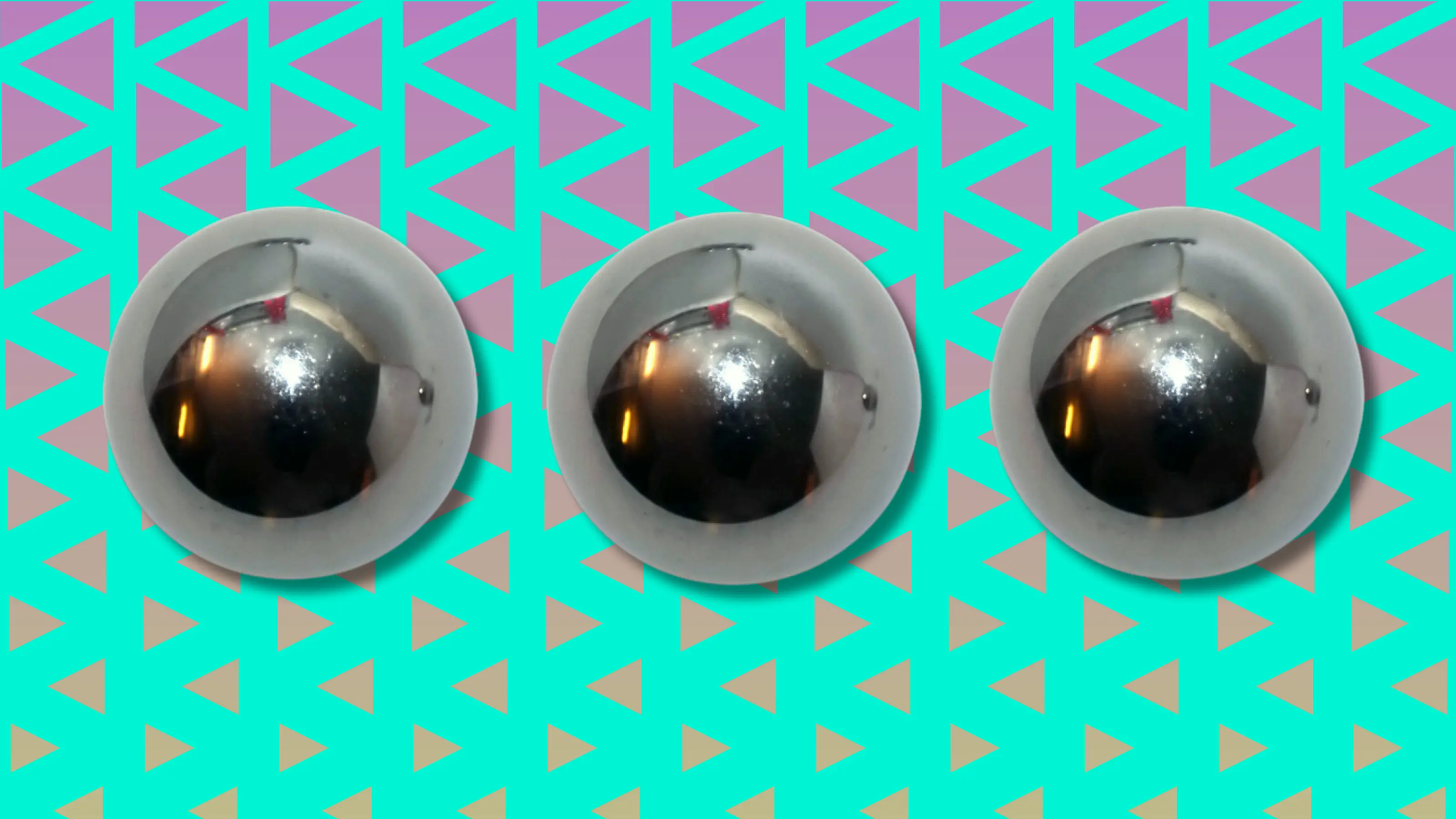 Three metallic silver spheres on teal and purple triangle background