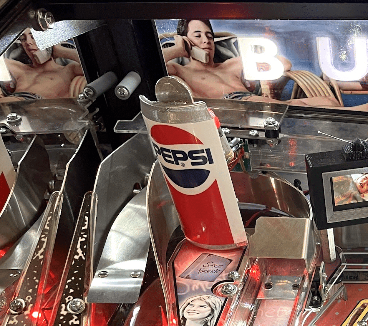 Pepsi bottle inside intricate machine with reflective surfaces and red lighting