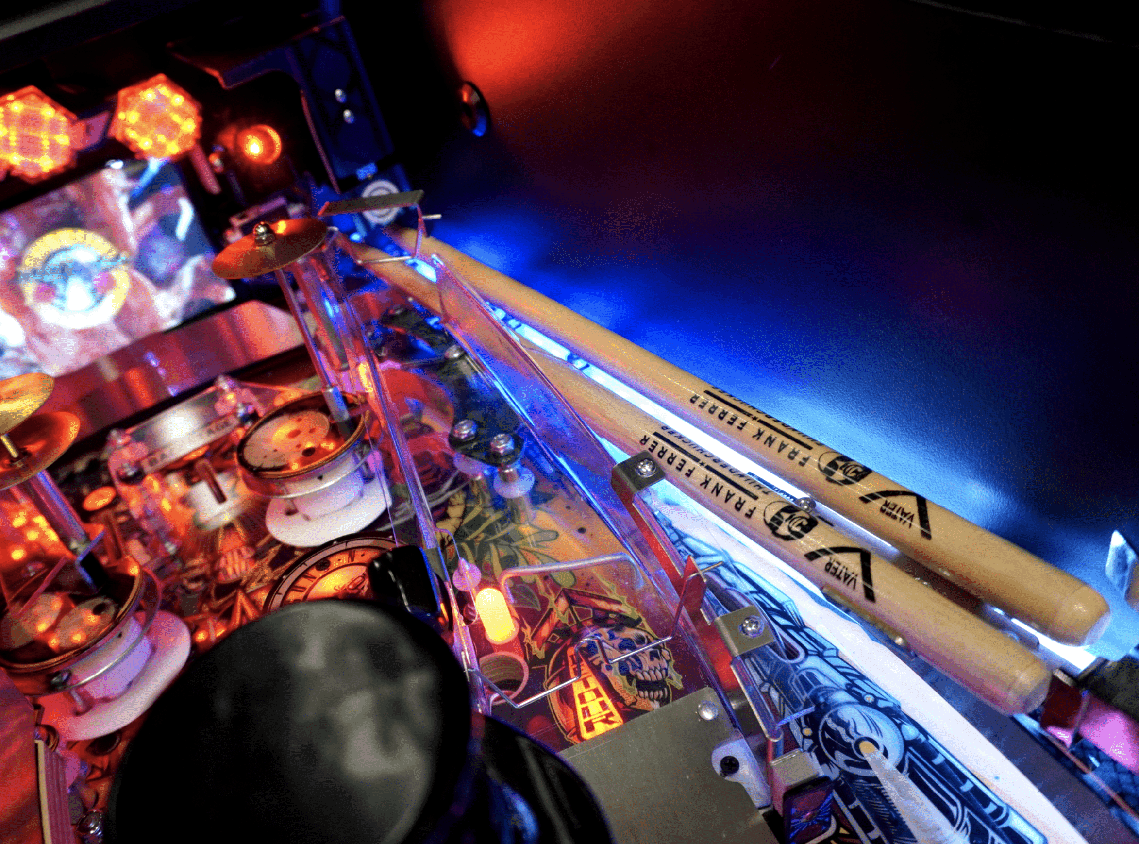 Pinball machine with colorful lights, detailed playfield, and drumsticks
