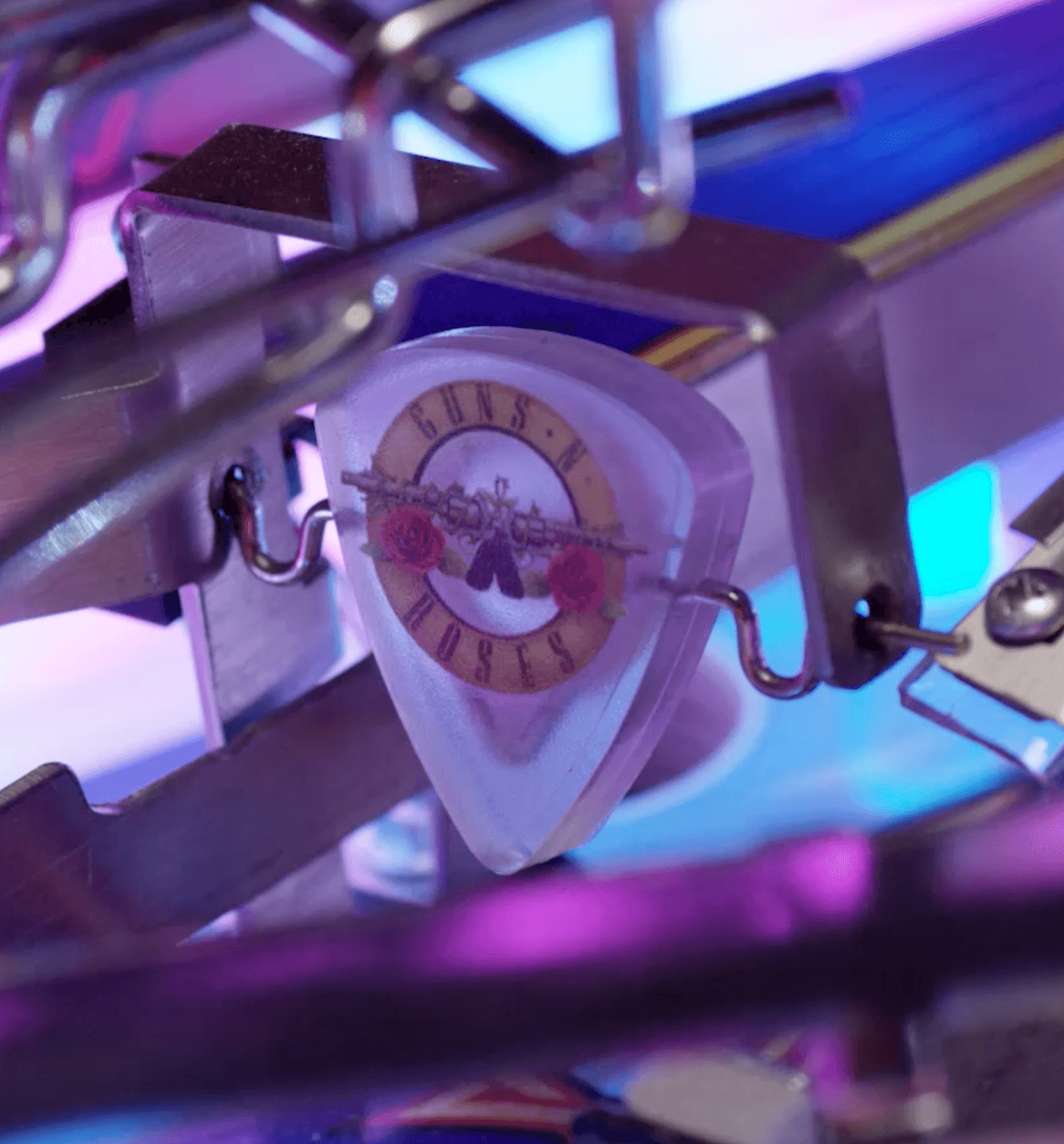 Guns N' Roses guitar pick with band logo mounted on metallic stand