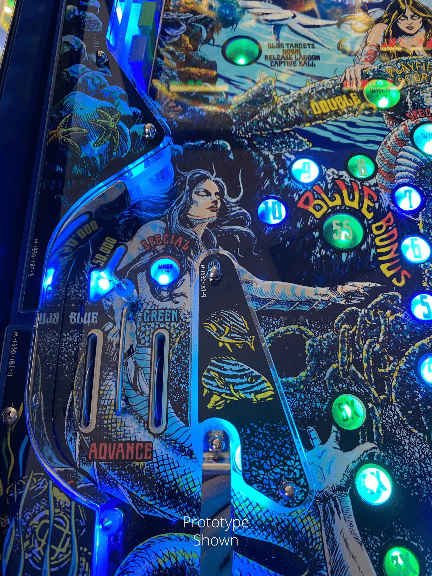Pinball machine backglass with mythical woman, blue lights, and game targets