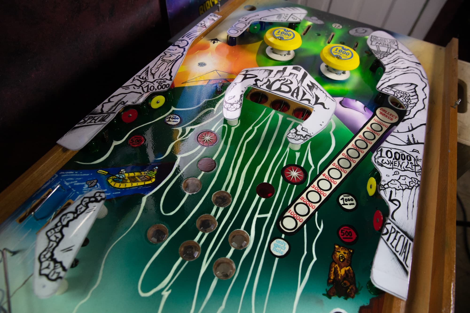 Colorful pinball machine playfield with buttons, lights, and scoring tracks