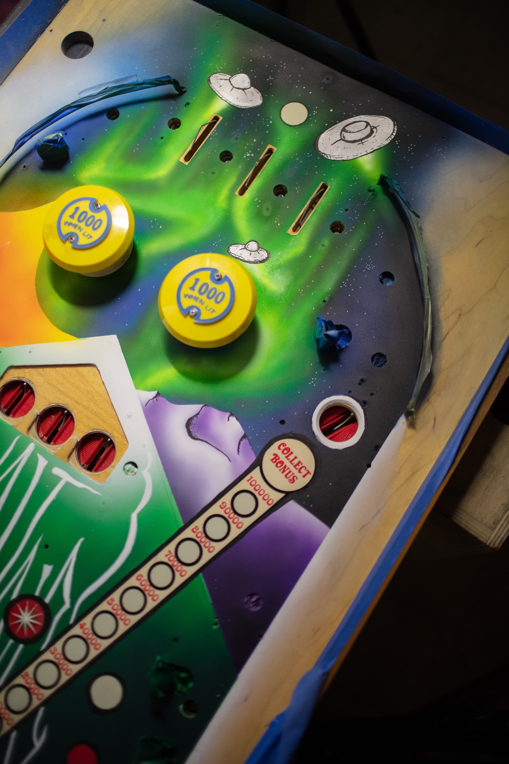 Retro pinball machine with UFOs, colorful buttons, and cosmic background