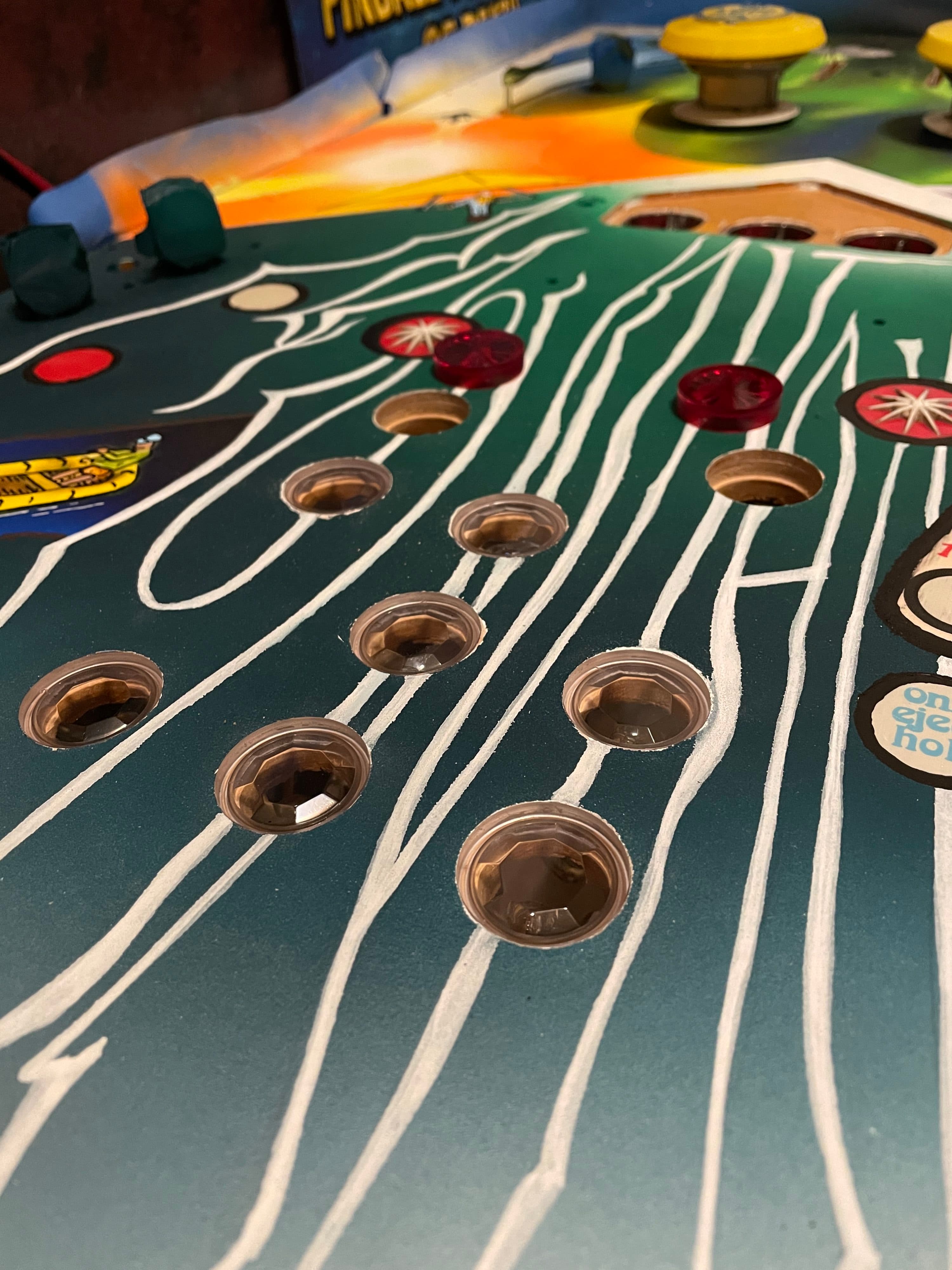Vintage pinball machine playfield with white lines and metallic holes