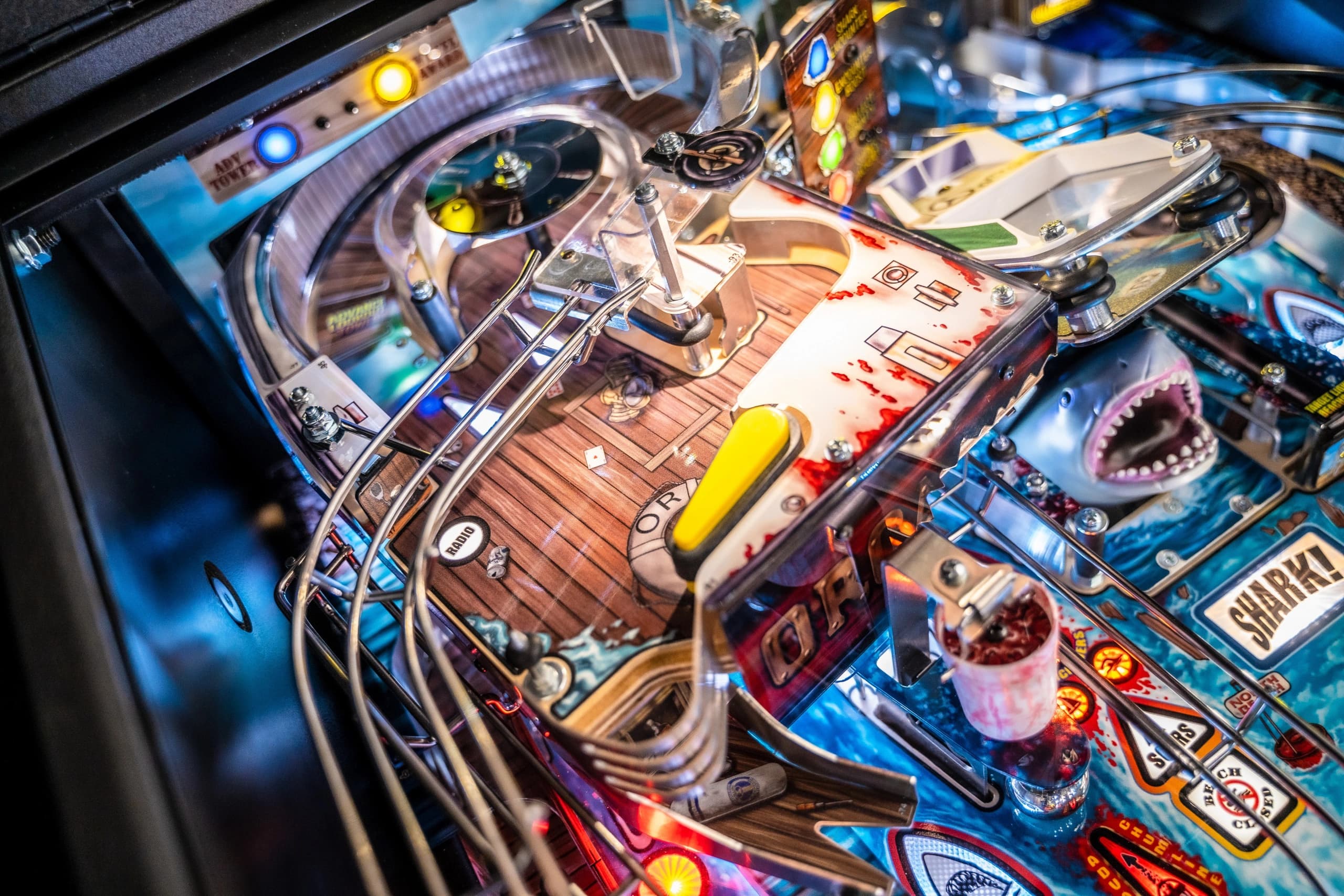 Close-up of a colorful pinball machine with flippers, lights, and shark theme