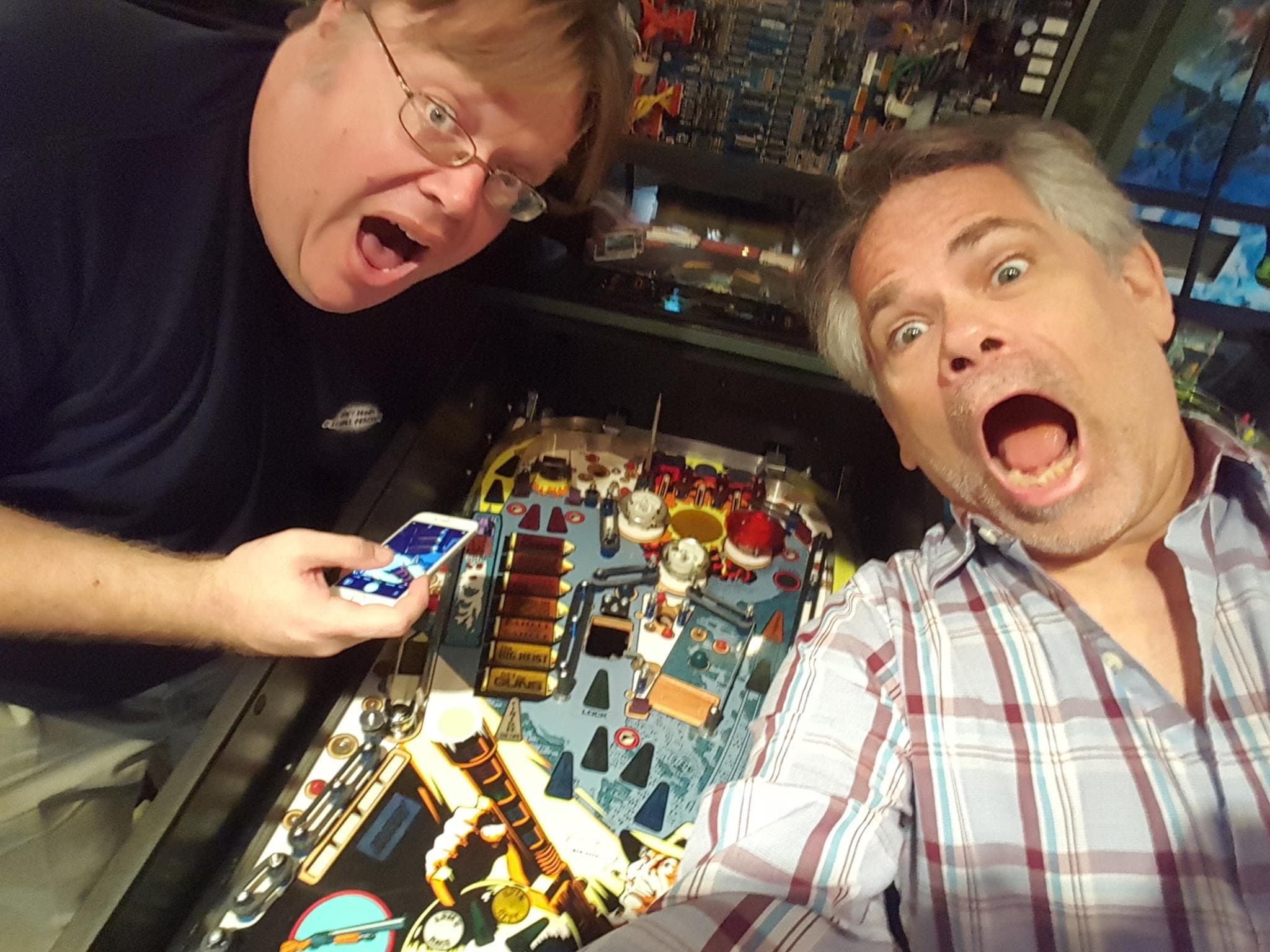 Two excited people playing a complex retro pinball machine