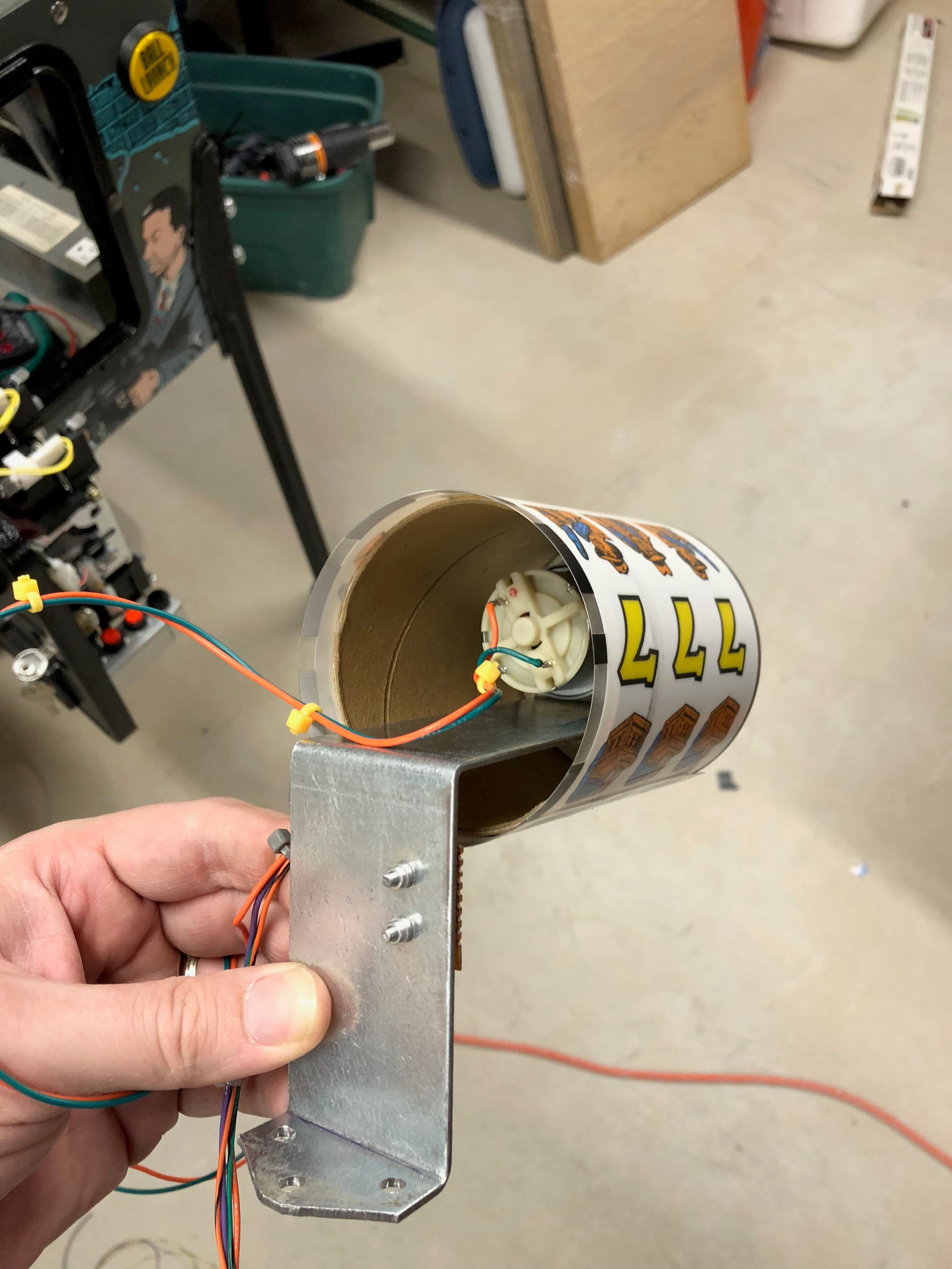 Mechanical device with metal bracket, wires, and coffee cup-like cylinder