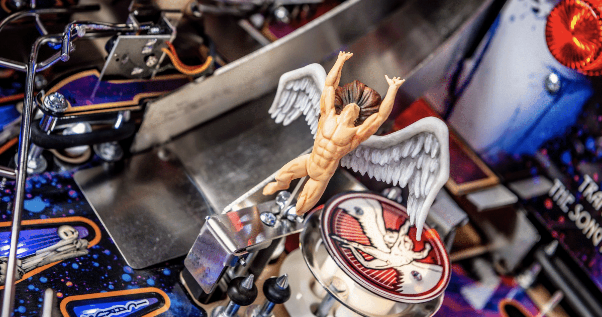 Winged muscular figure statue on a complex mechanical workshop background