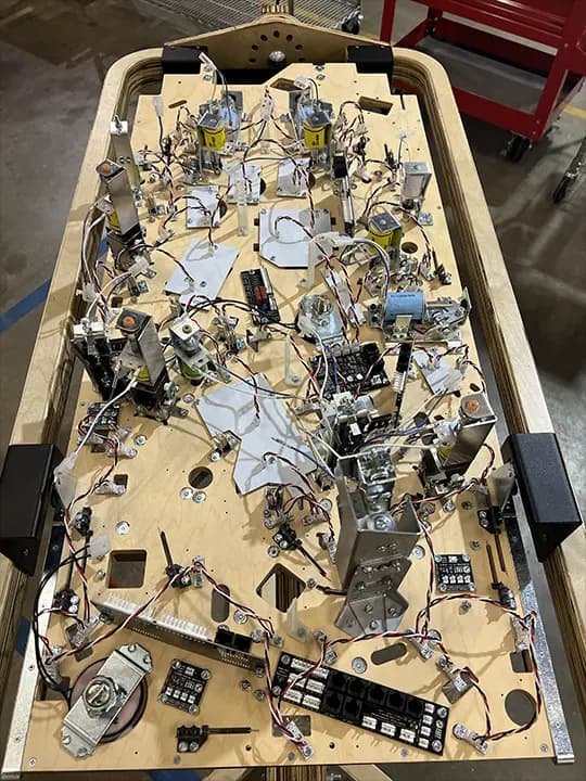 Complex pinball machine interior with intricate electronic components and wiring