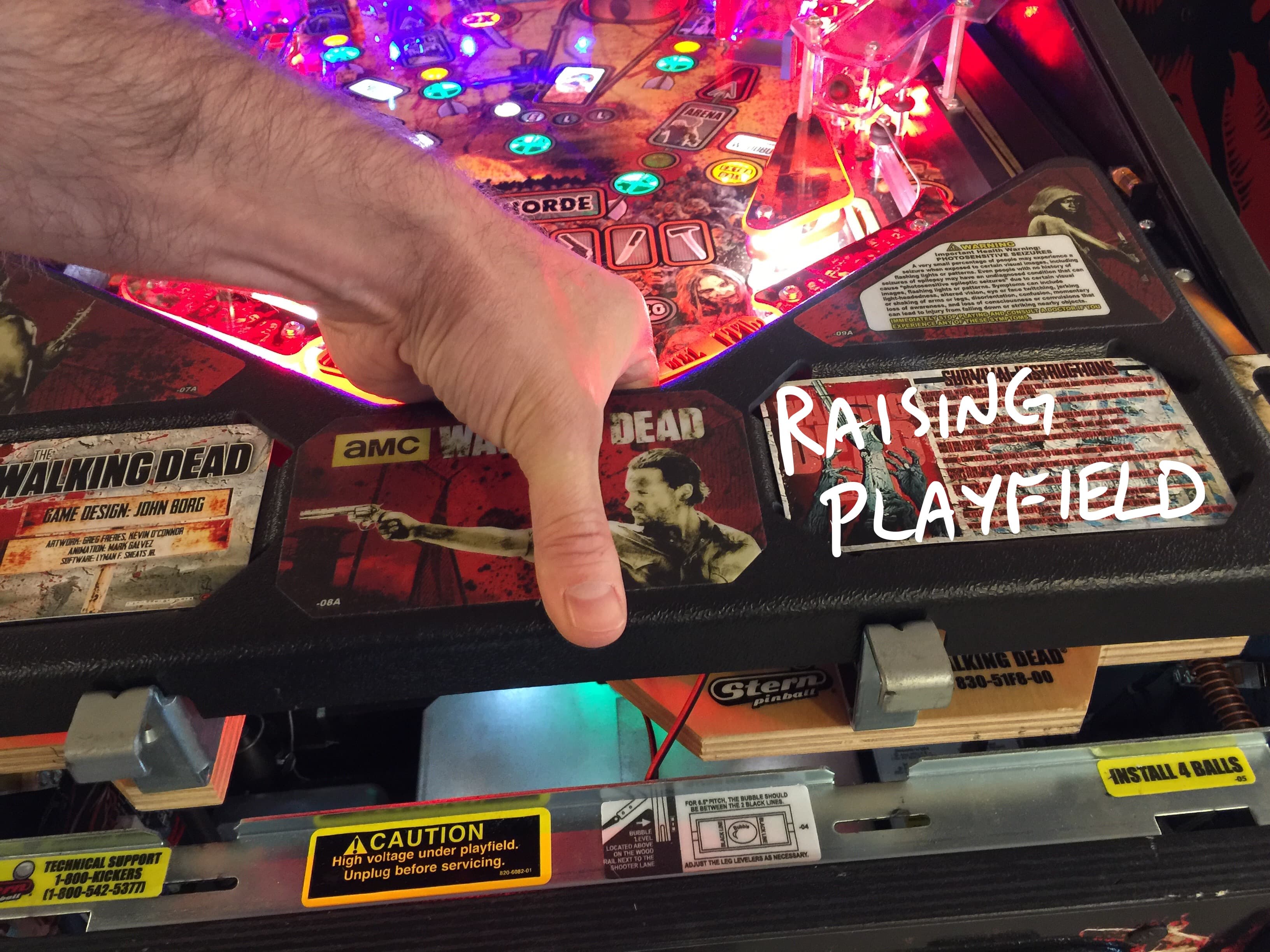 The Walking Dead pinball machine with colorful lights and hand touching playfield