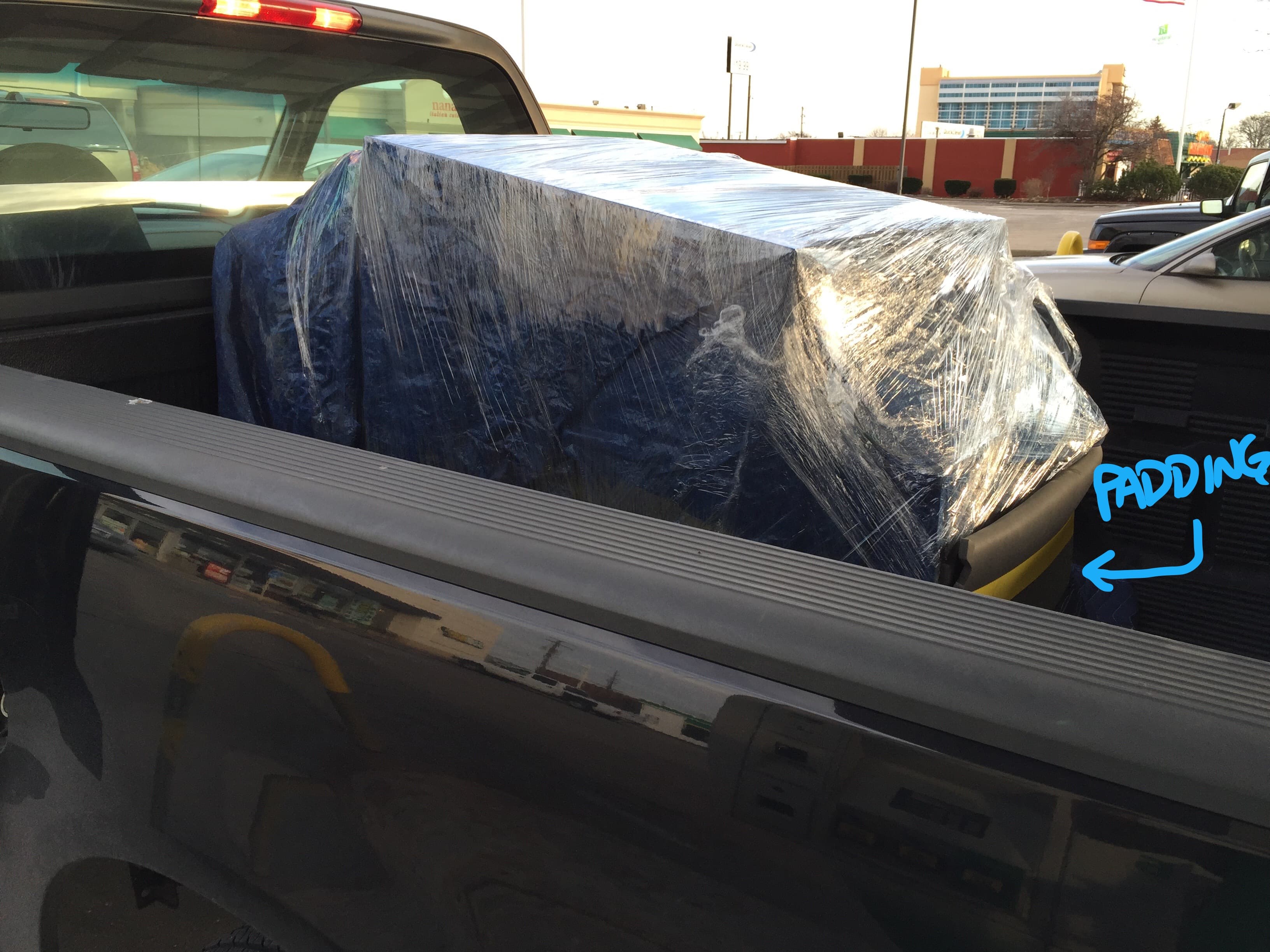 Large item wrapped in plastic stretch film secured in pickup truck bed