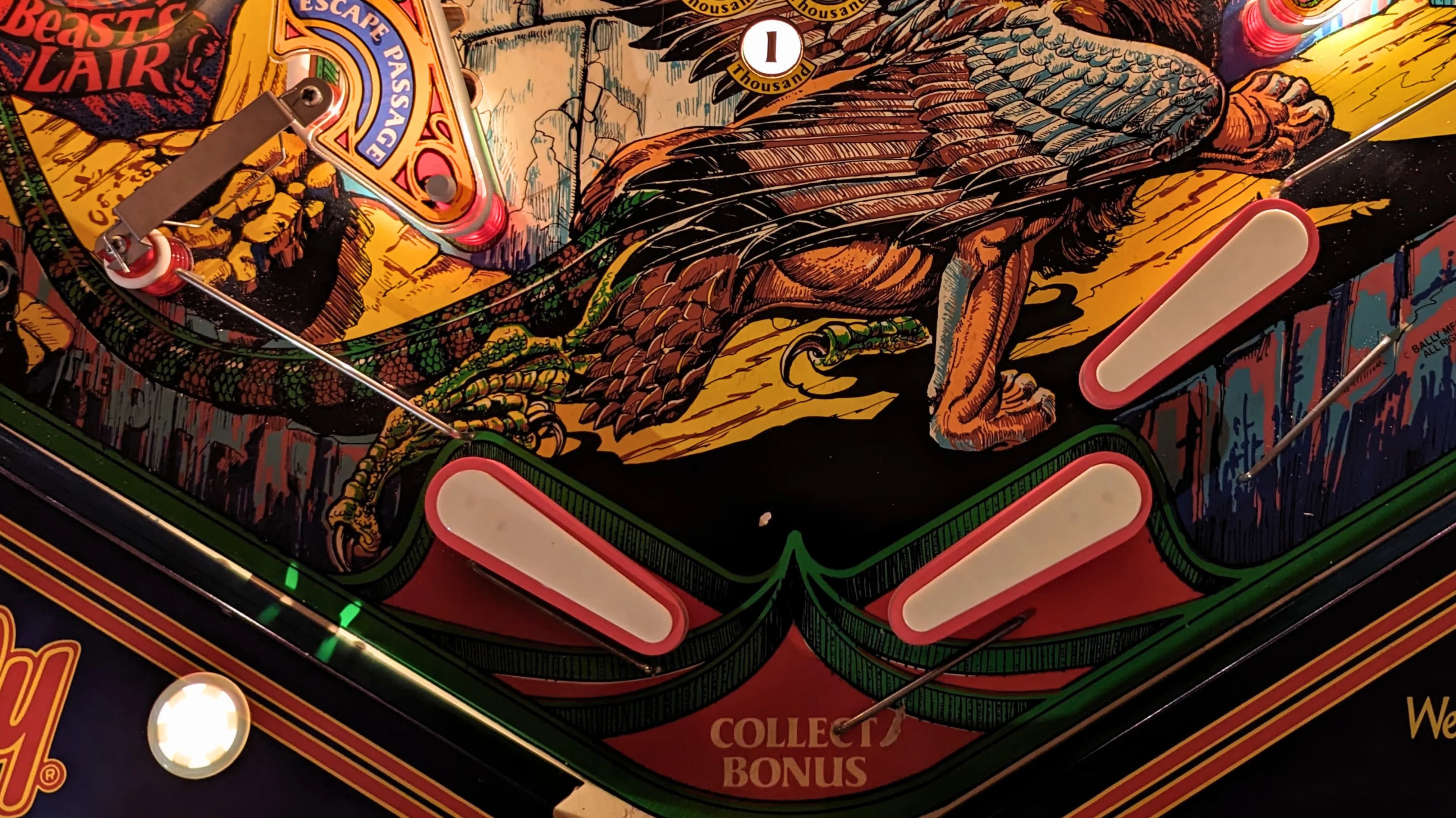 Colorful pinball machine with mythical winged creature and bumpers