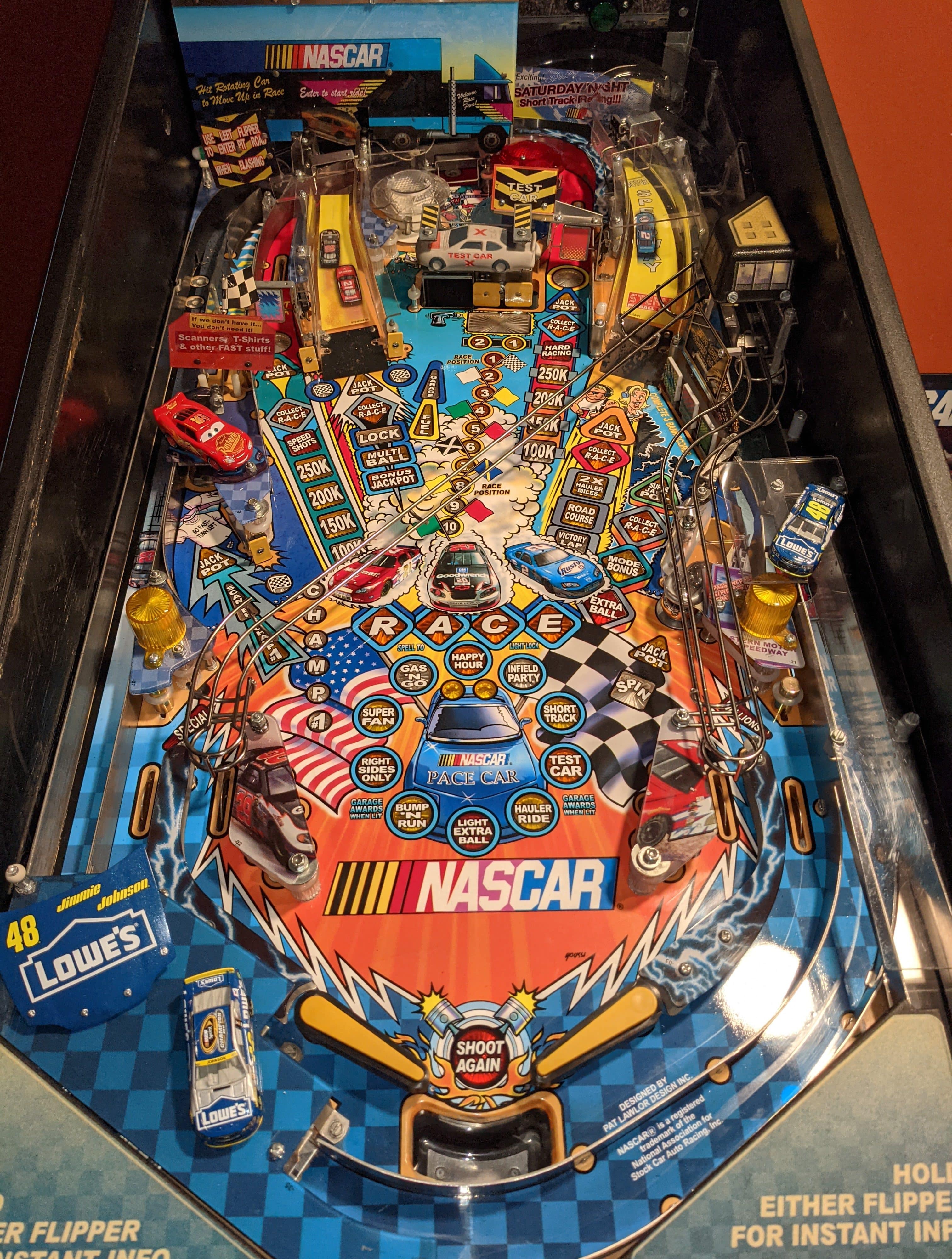 NASCAR-themed pinball machine with colorful race cars and scoring zones