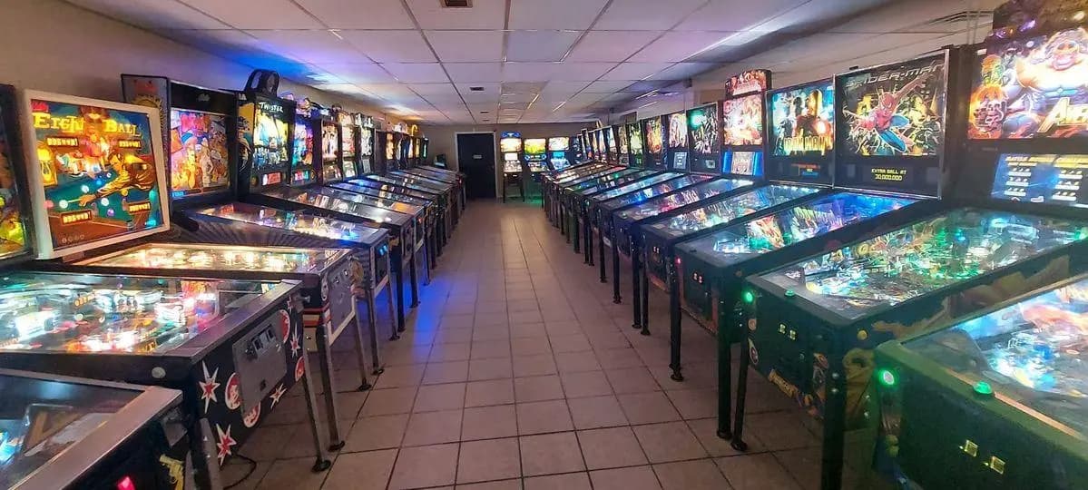 Two very long rows of pinball machines with more on the far wall