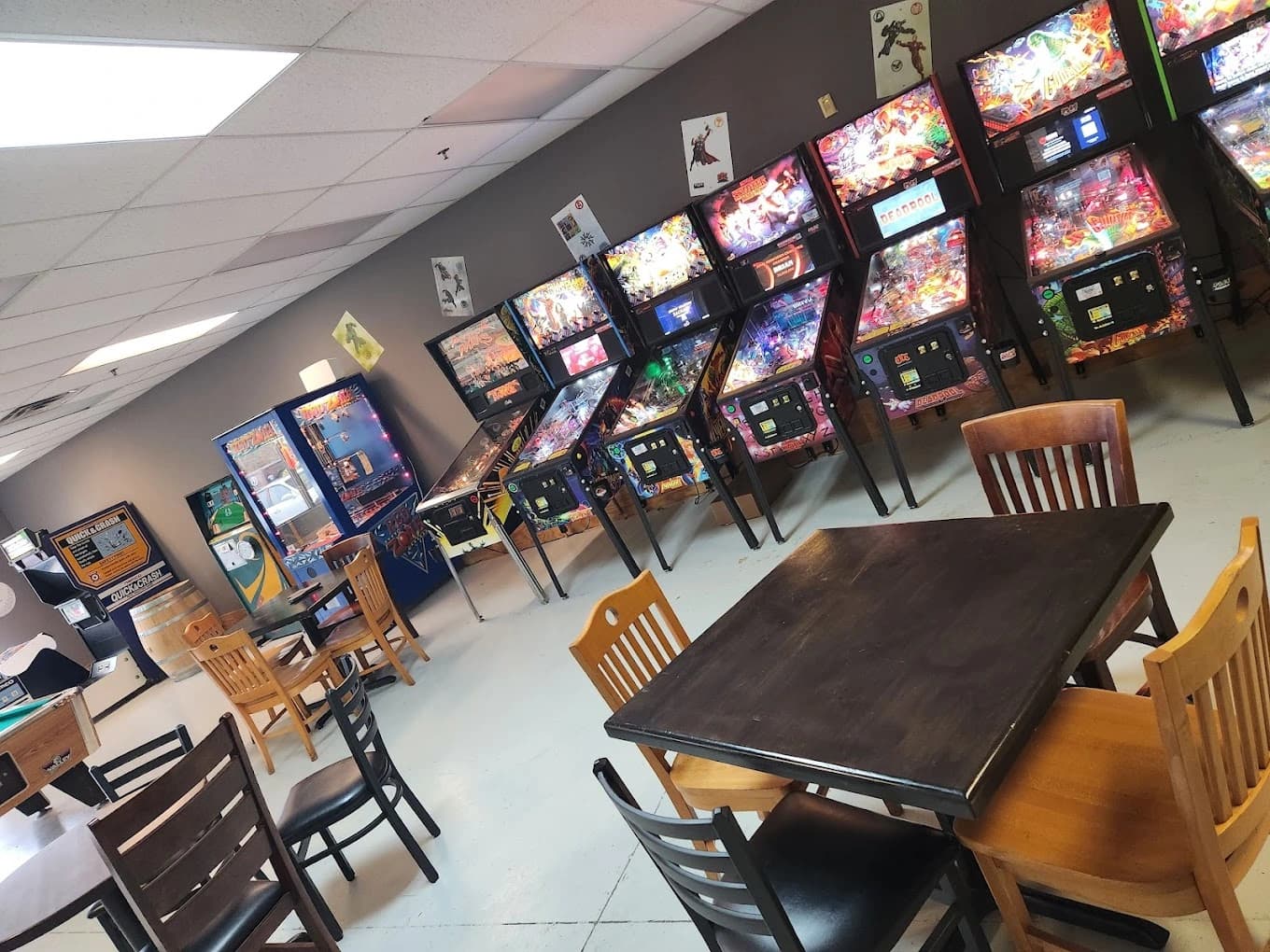Pinball machines and wooden tables in a game room arcade