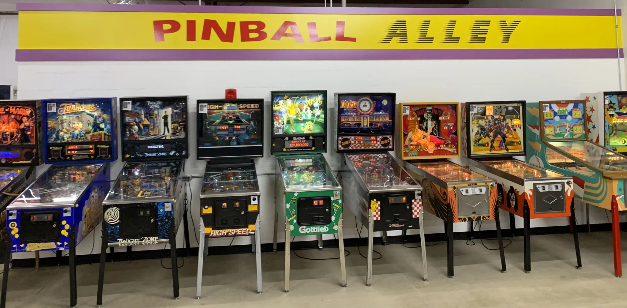 Vintage pinball machines lined up in colorful Pinball Alley arcade