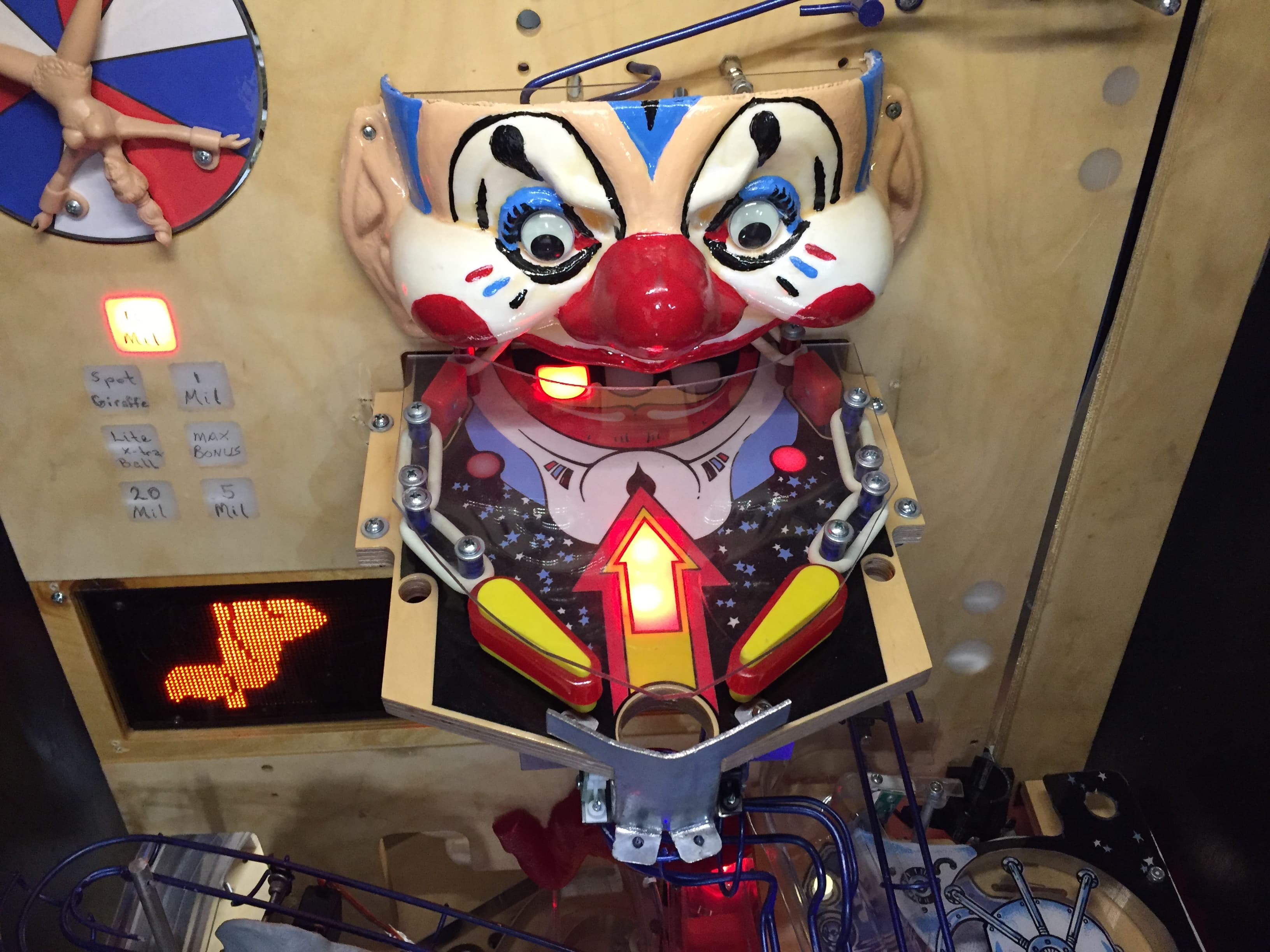Creepy clown pinball machine head with glowing red eyes and nose