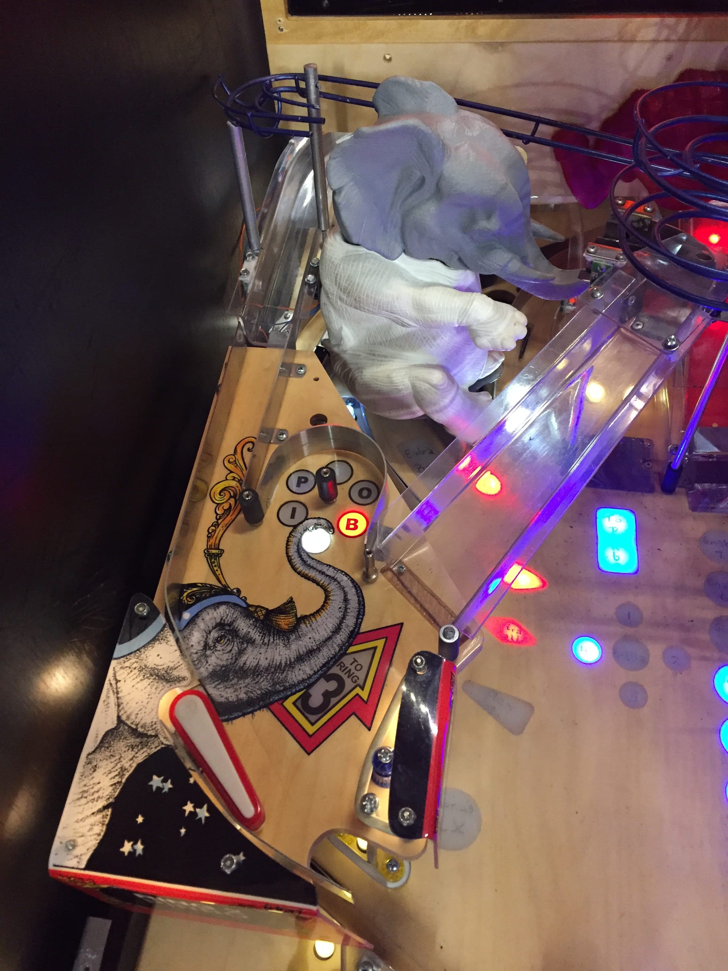 Pinball machine with elephant graphic, colorful lights, and clear plastic components