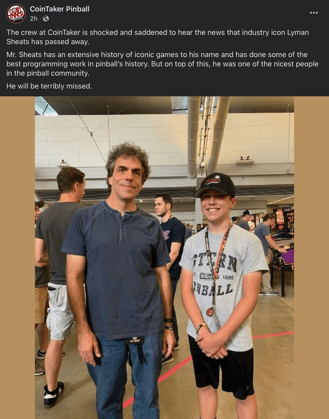Two people standing together at a pinball event, surrounded by pinball machines