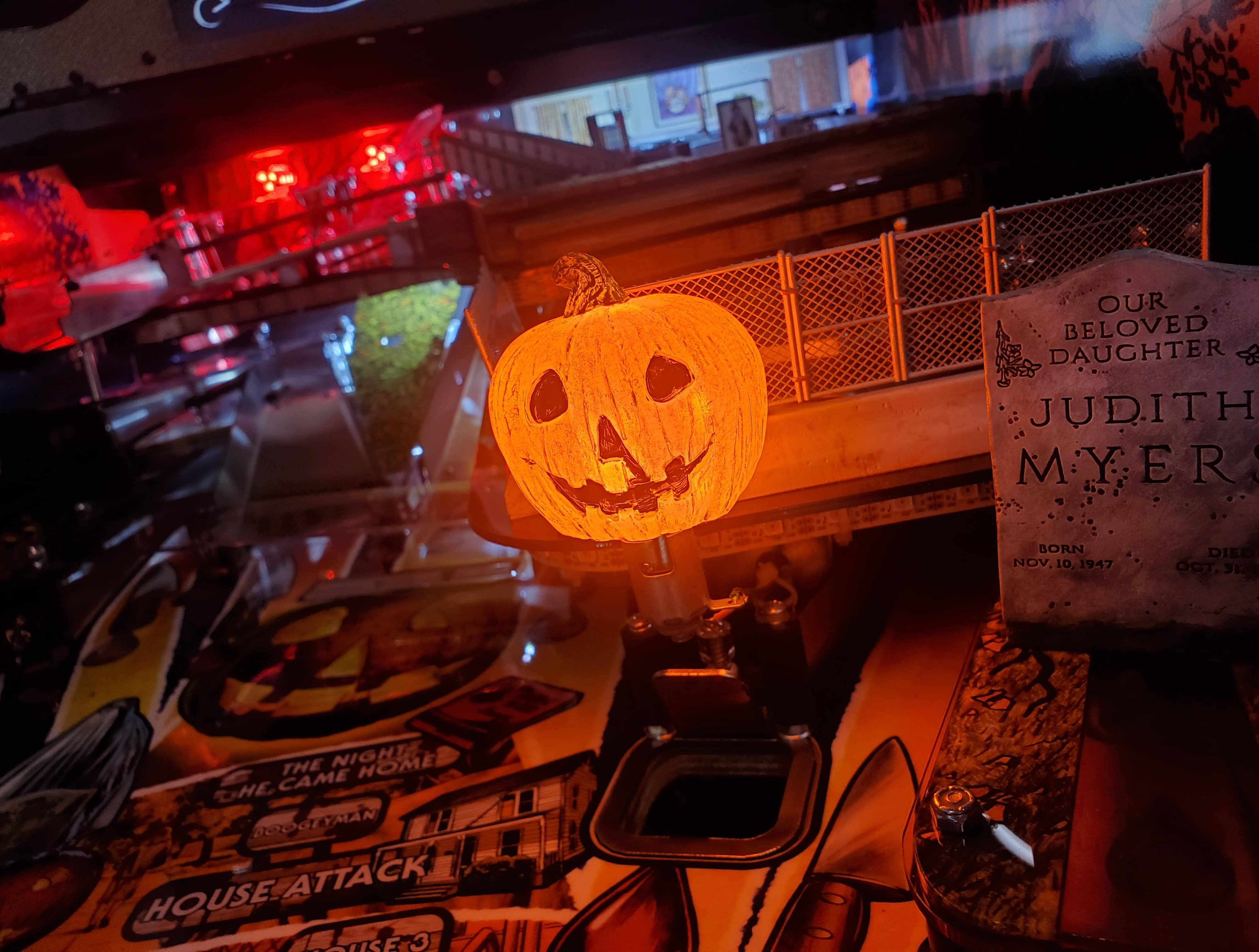 Jack-o'-lantern glowing beside Halloween movie poster and gravestone
