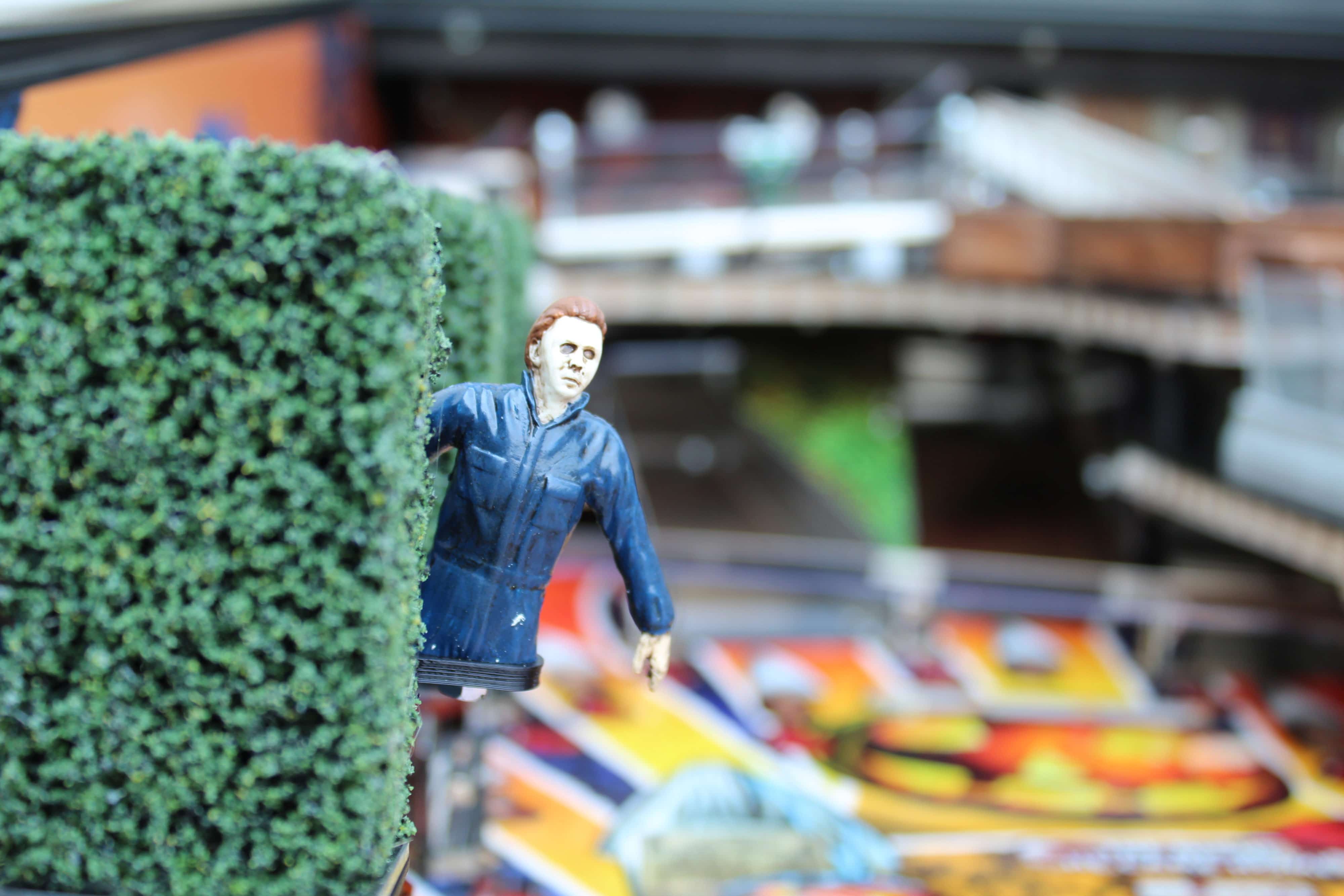 Small figurine of horror movie character near green hedge and blurry background