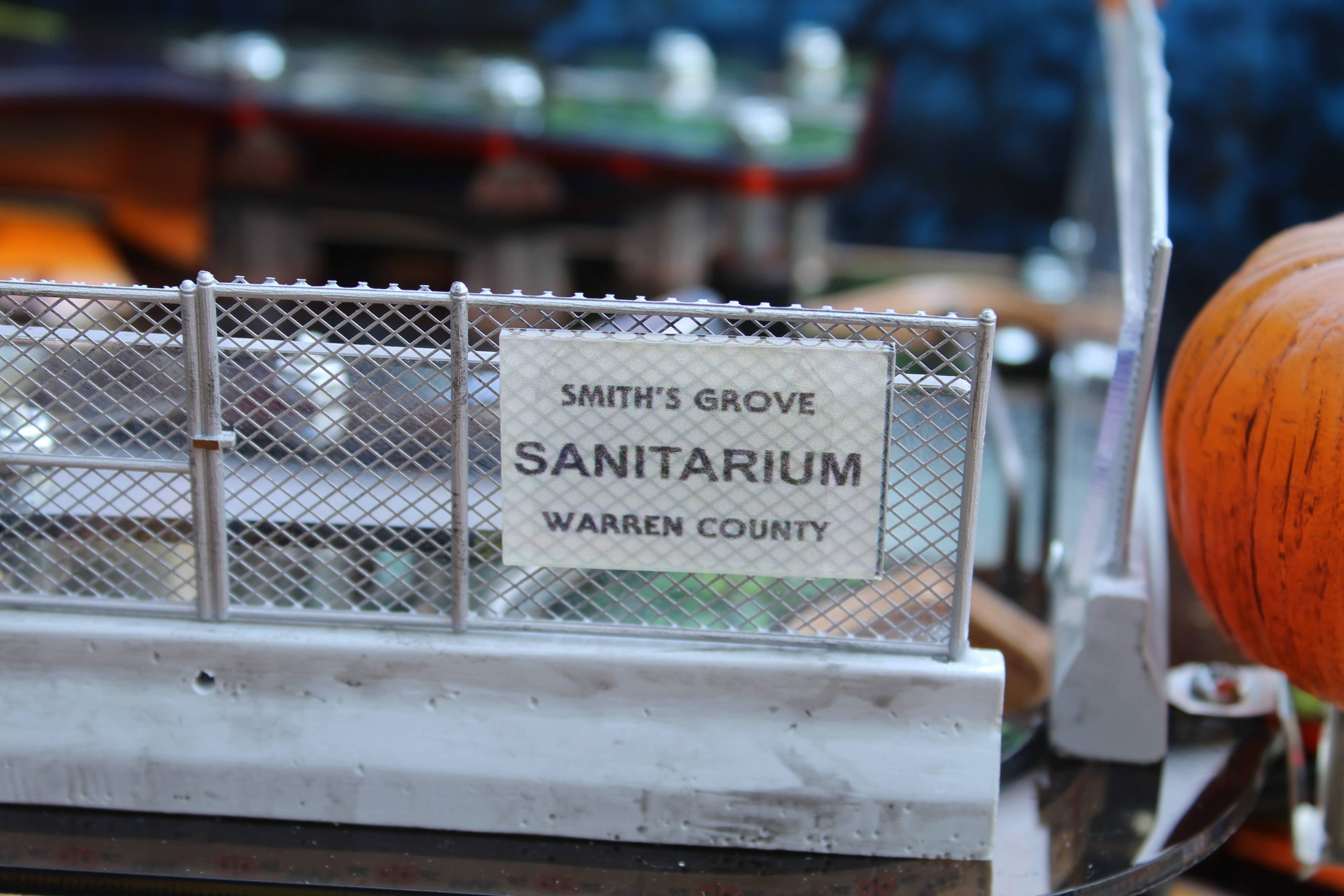 Smith's Grove Sanitarium sign on metal fence with pumpkin nearby